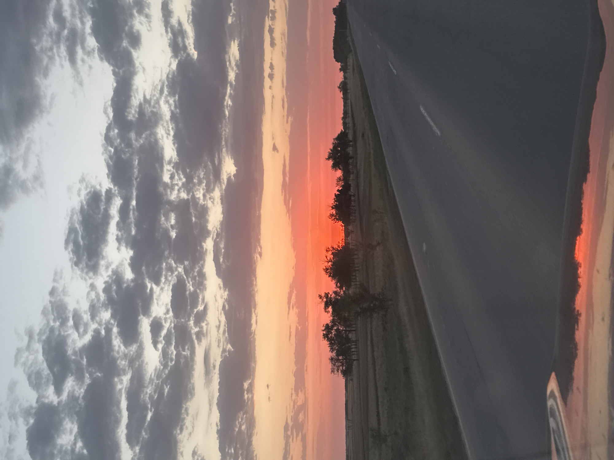 Sunset over a Kazakh highway, sky ablaze with orange and pink