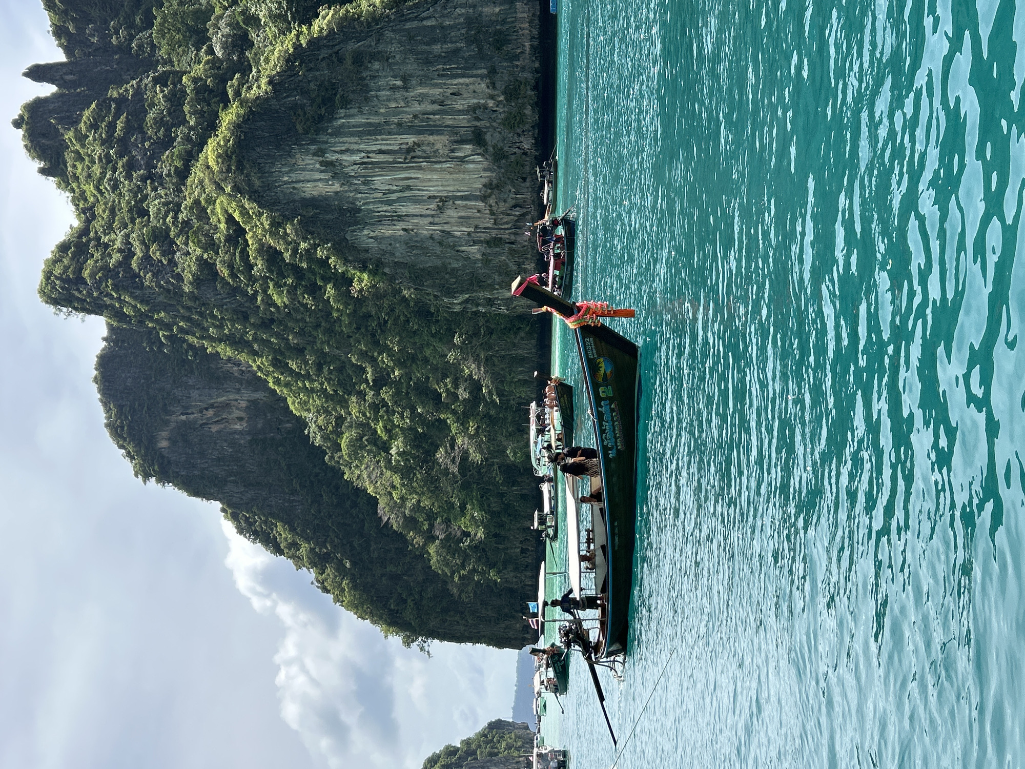 Boats and swimmers in Ao Nang's limestone-framed bay