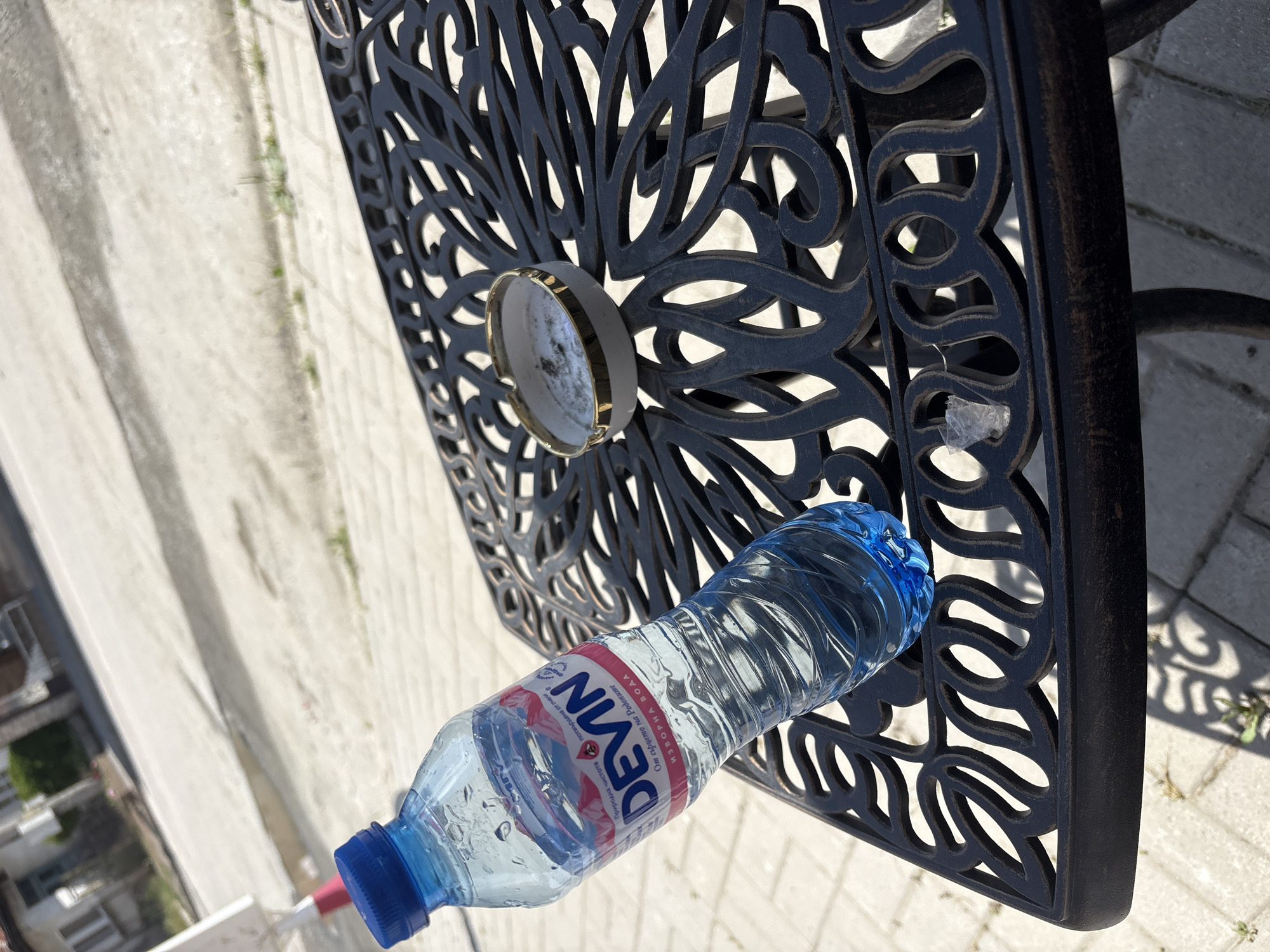 Outdoor table setup: water, cigarettes, and a lighter near a Bike Center