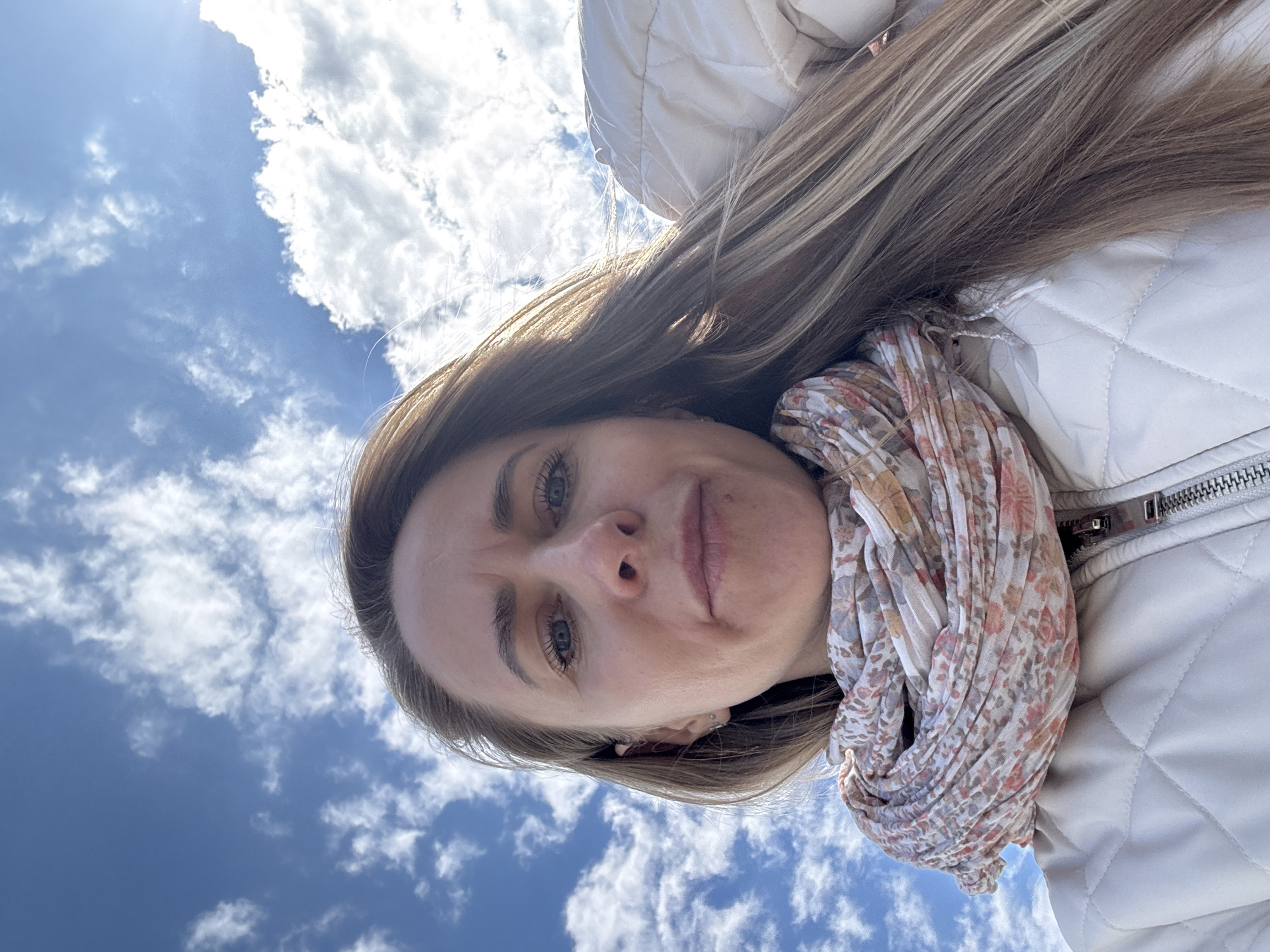 Woman takes upward-angle selfies against blue sky in Chaikovsky