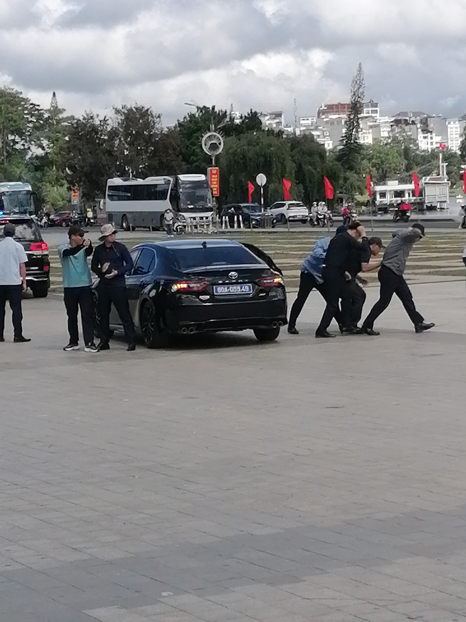 Martial arts session underway on outdoor plaza near parked sedan