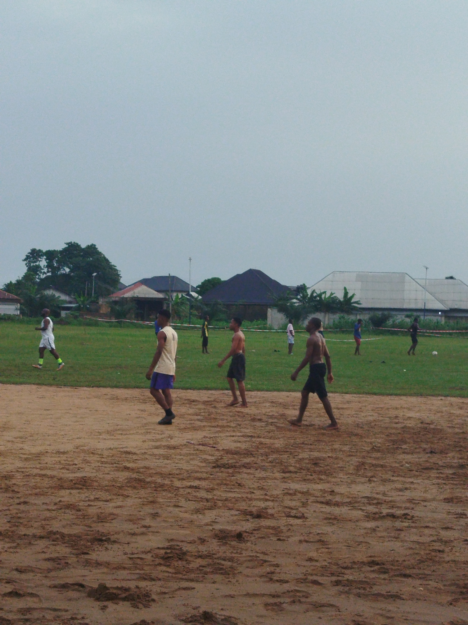 Young men play soccer on muddy field in Nigeria