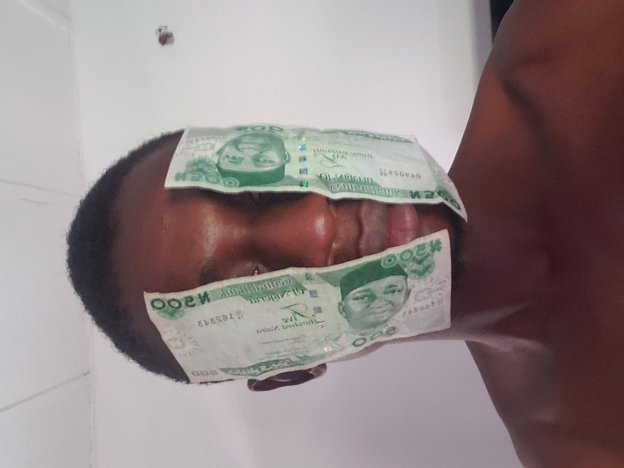 Young man poses with Nigerian banknotes in Adonkolo