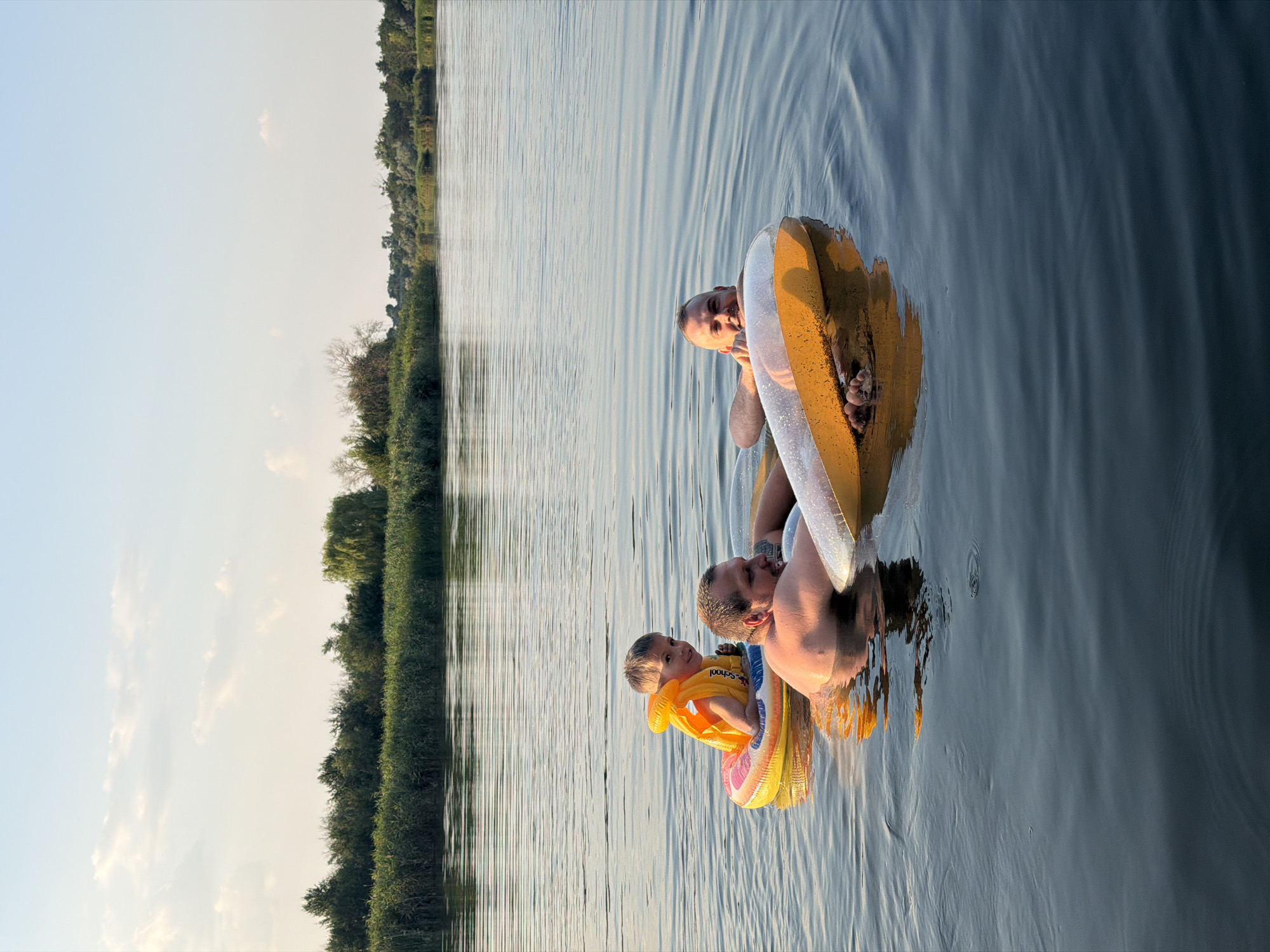 Lake day in Ukraine: swimmers, a pier, and a dog in a shark vest