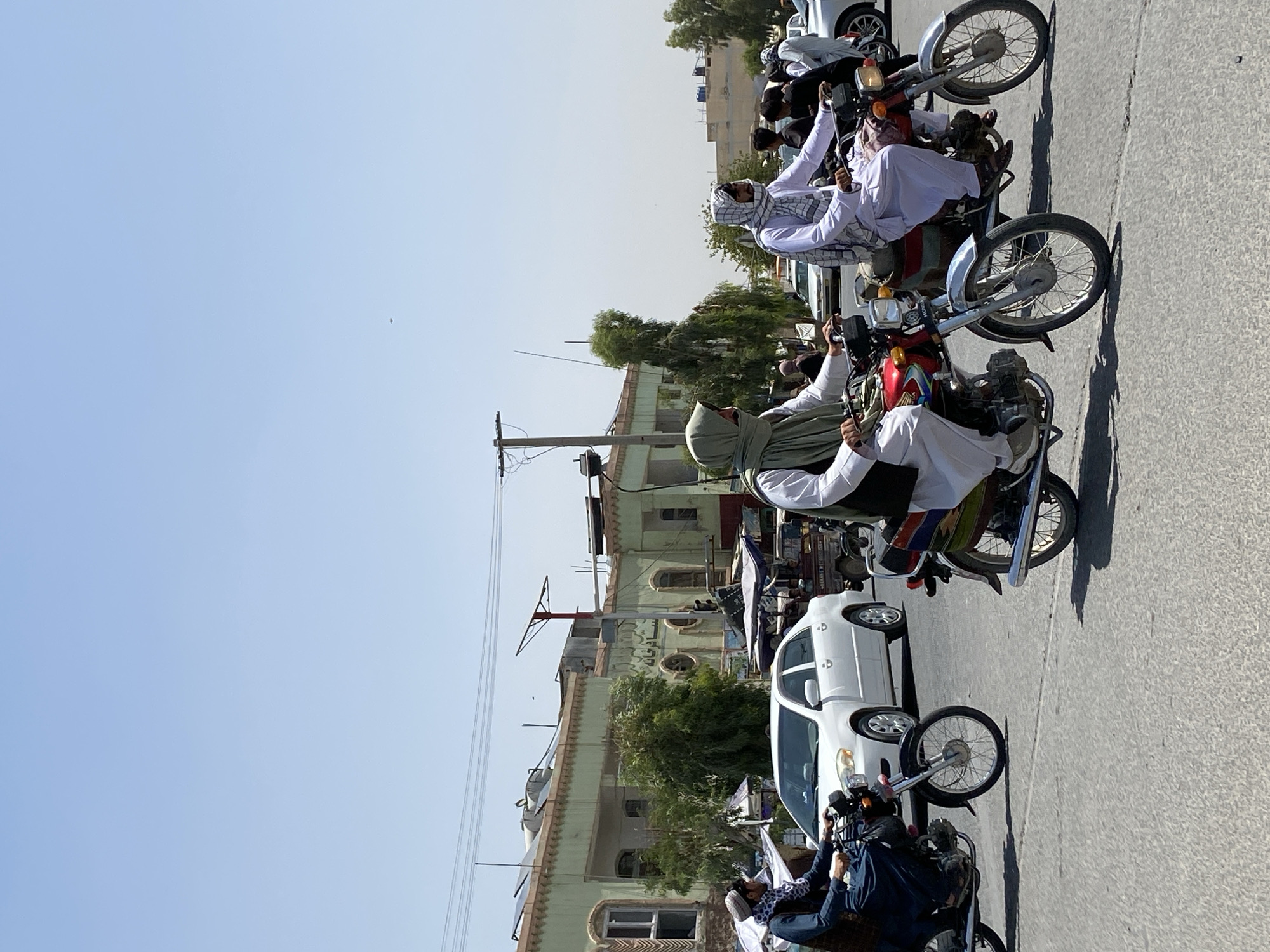 Motorcycles moving through a sunny Kandahar street