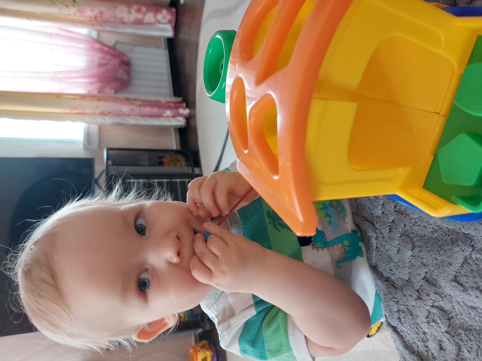 Child plays with toys alongside cat in Russian home