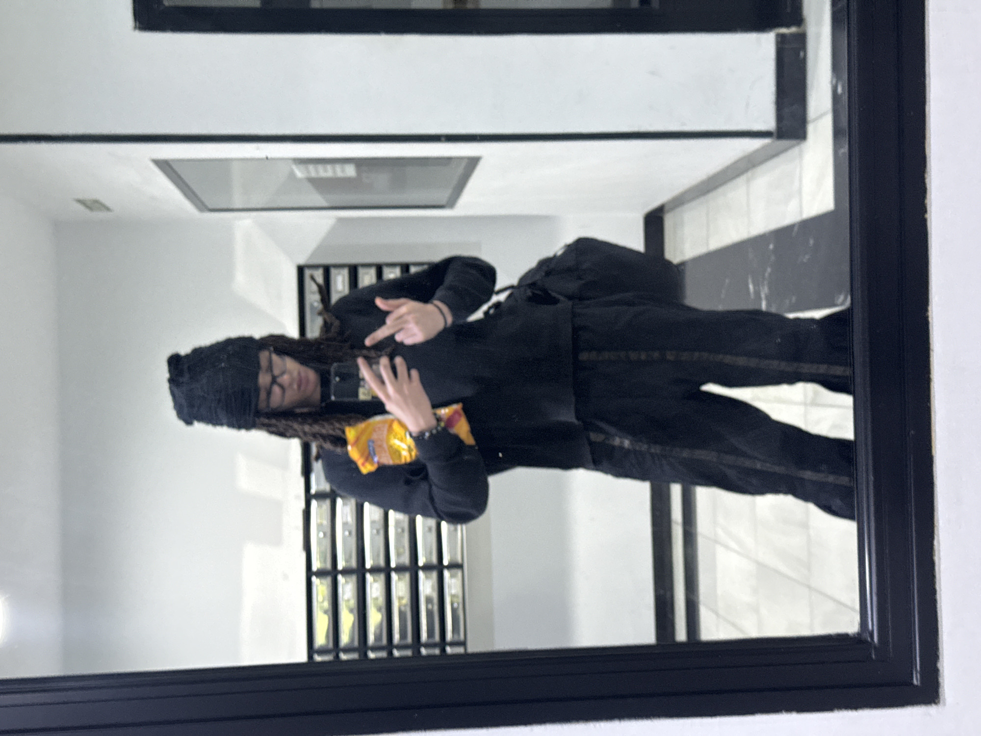 Person takes mirror selfies in Madrid apartment building hallway