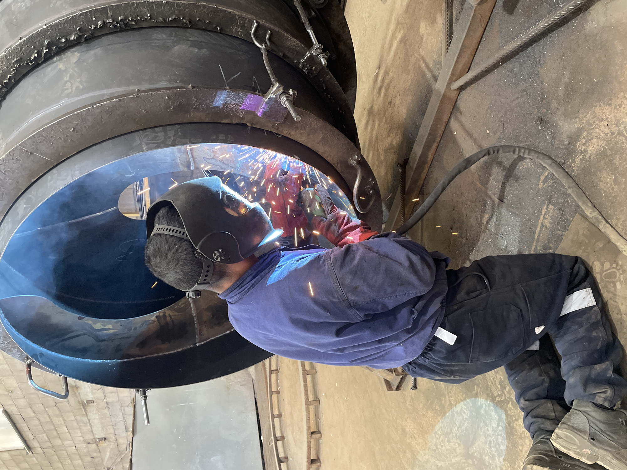 Welder performs arc welding in industrial workshop in Tomba