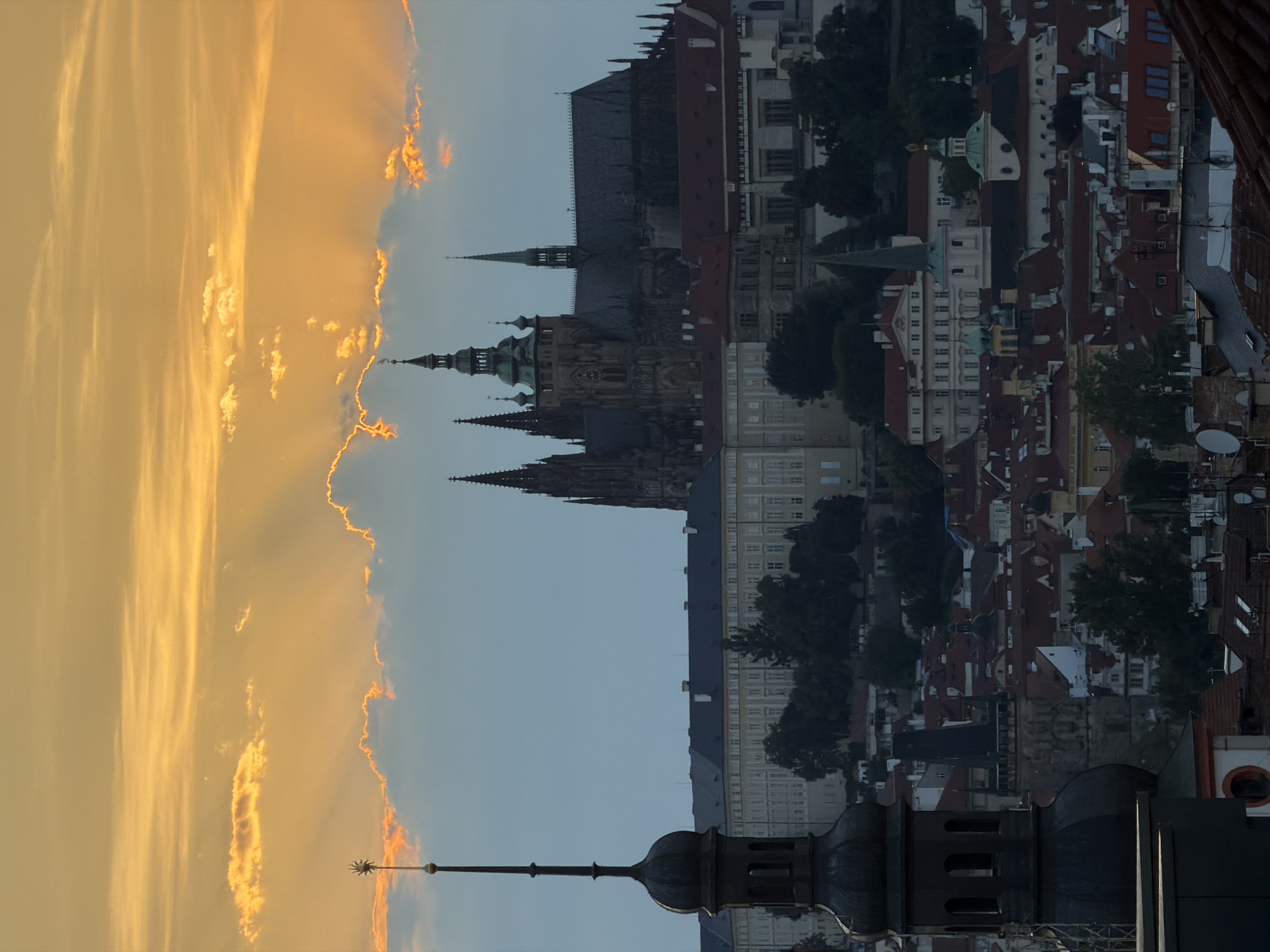 Prague's rooftops glow under a dramatic dusk sky