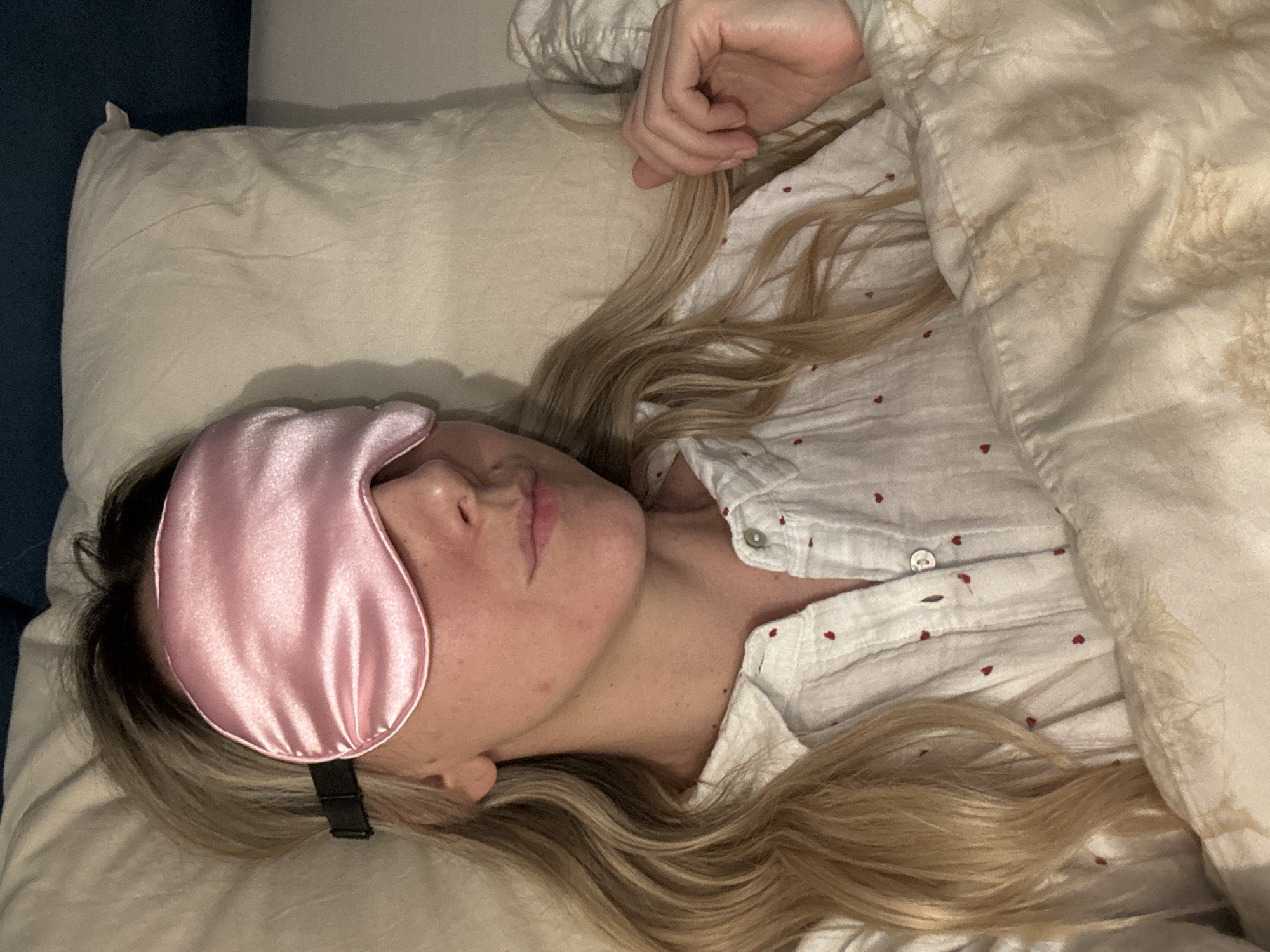 Woman rests in bed with sleep mask in Latvia