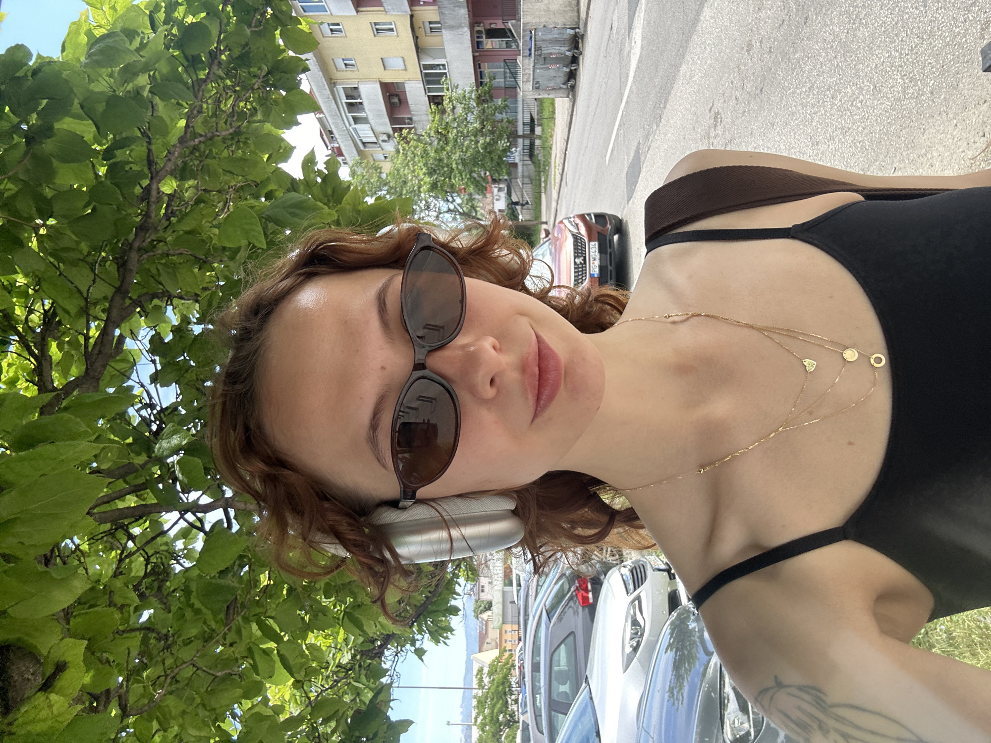 Woman takes selfie in Podgorica wearing sunglasses and headphones