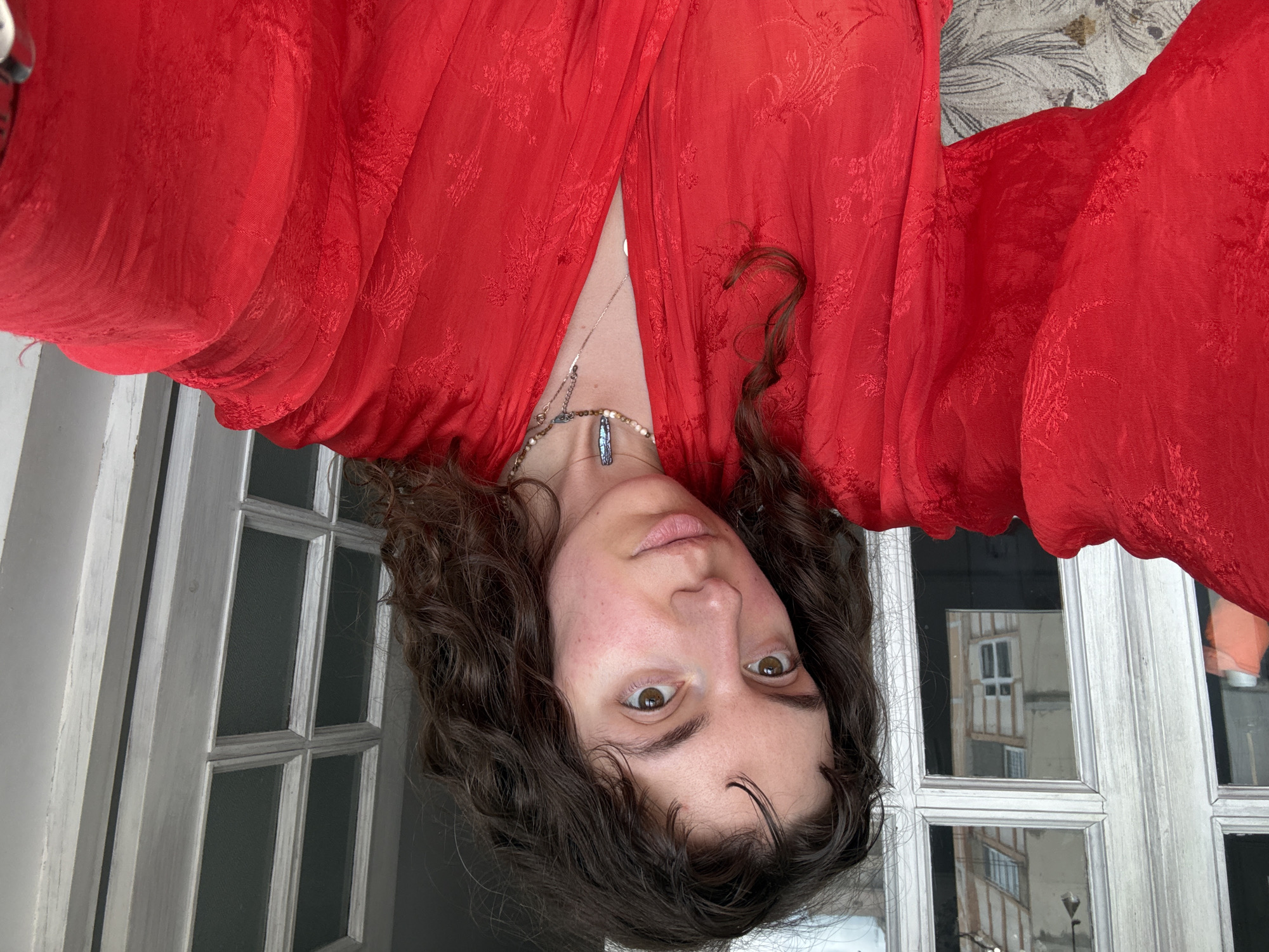 Woman in red robe juggles yellow fruits indoors