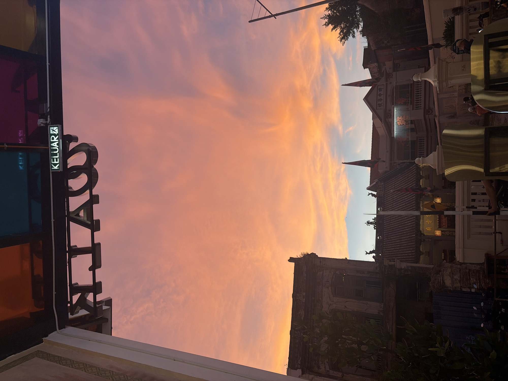 Dusk falls over a Southeast Asian street with a glowing exit sign