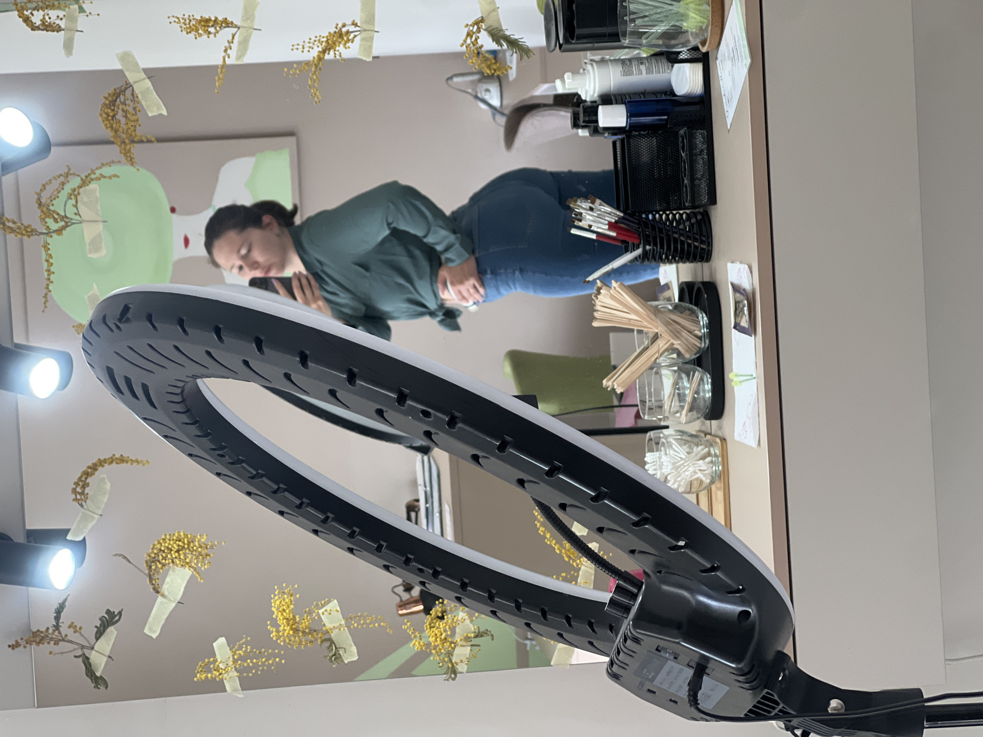 Woman uses phone near ring light setup in Podgorica room