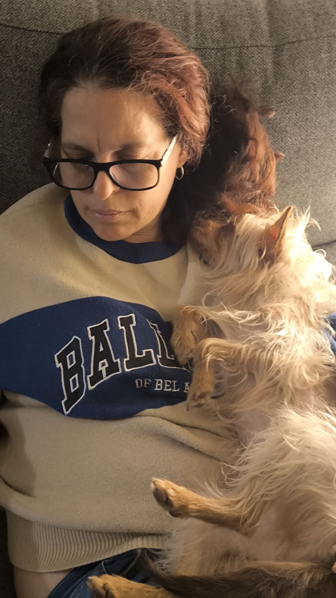 Woman relaxes with small dog on couch in Ripollet