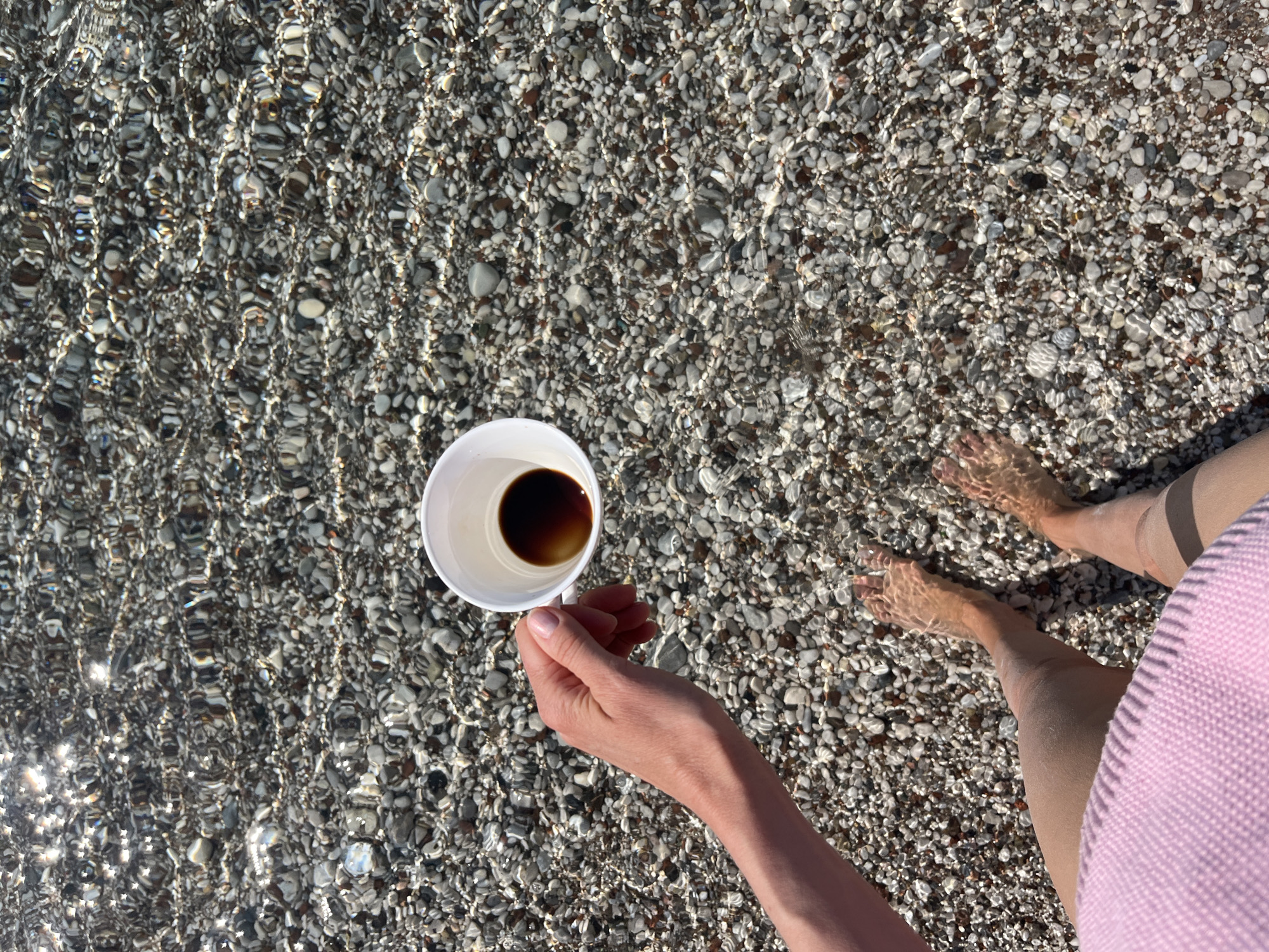 Woman enjoys morning coffee in shallow waters at Budva beach