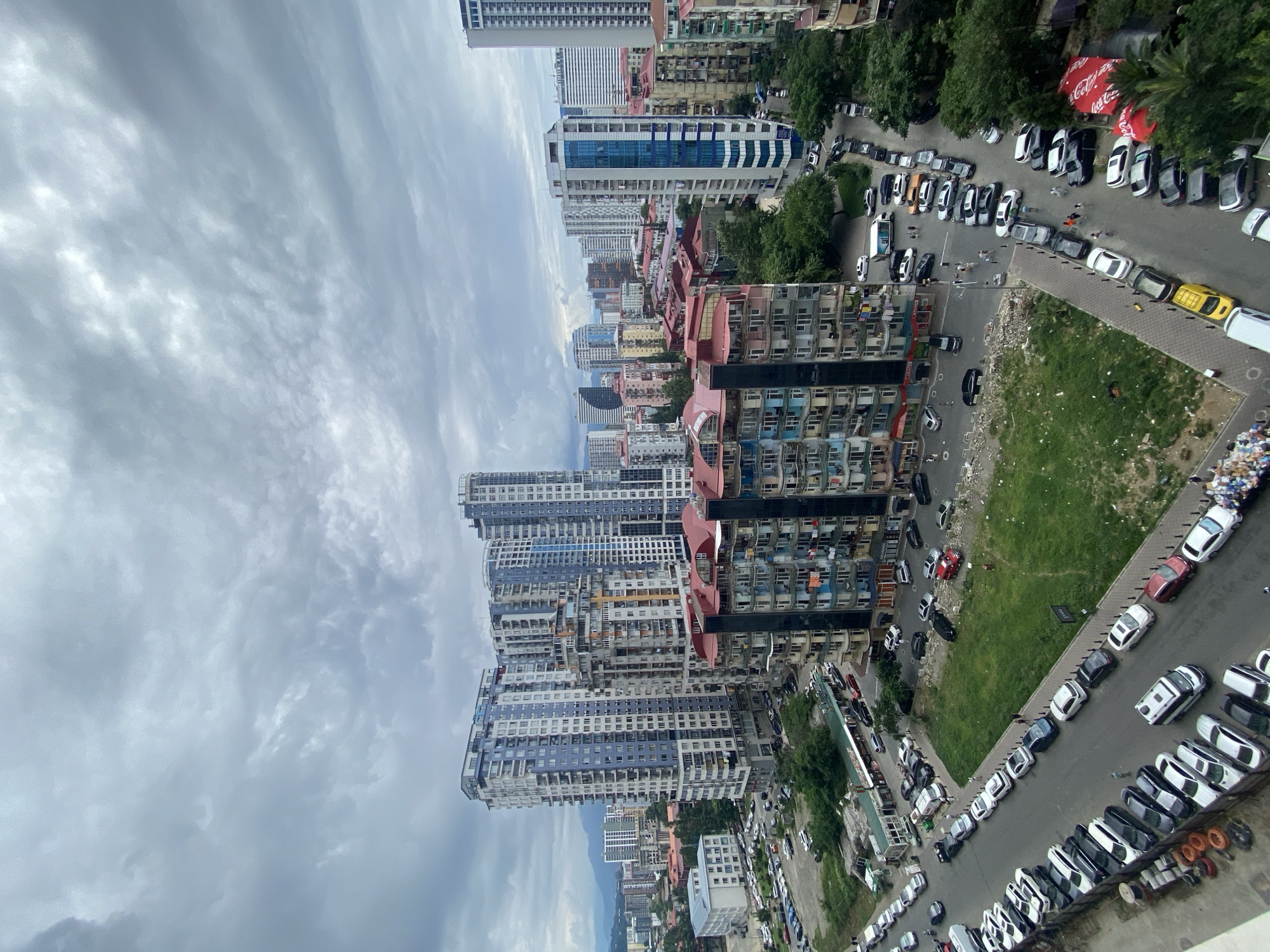 Quiet street lined with parked cars in cloudy Batumi