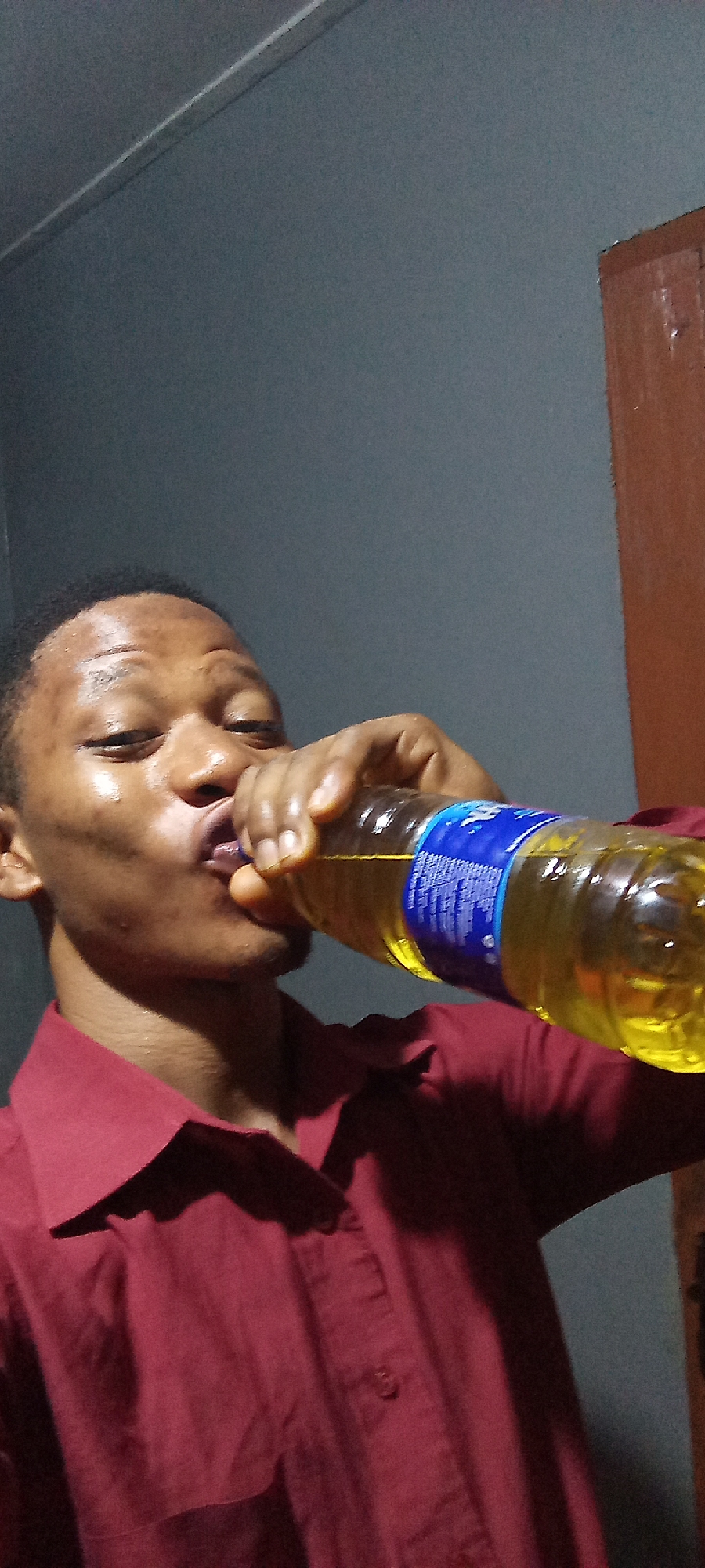 Person drinks yellow beverage from plastic bottle