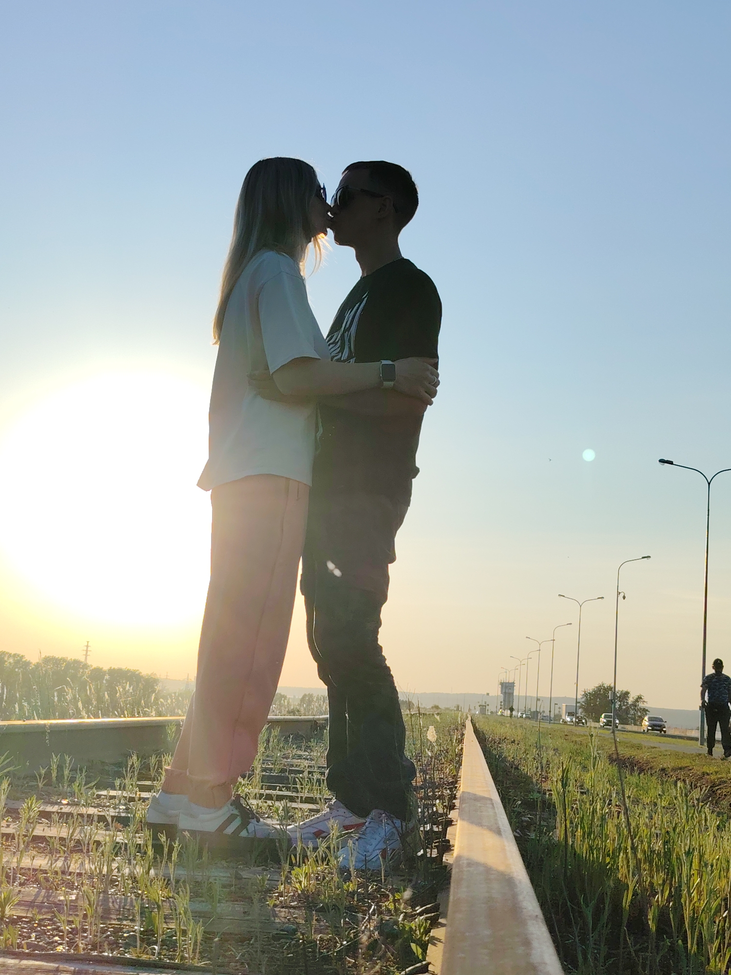 Couple stages sunset photography session on railway tracks in Chaikovsky