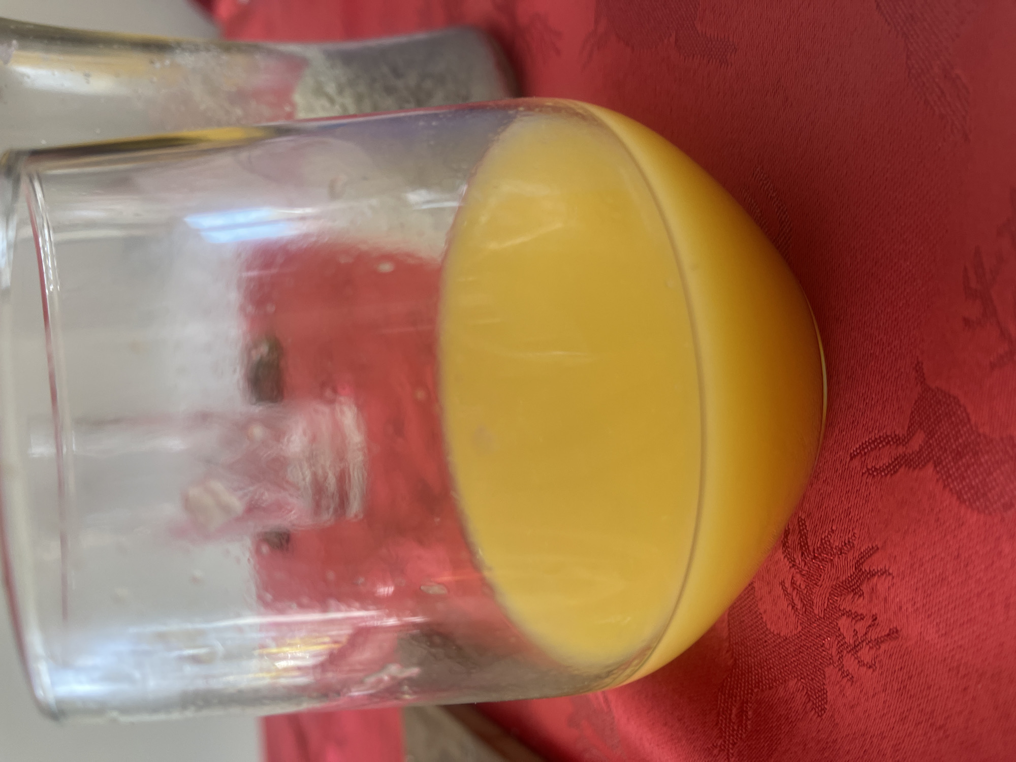 Glass of orange juice spotted on red tablecloth in Maidstone