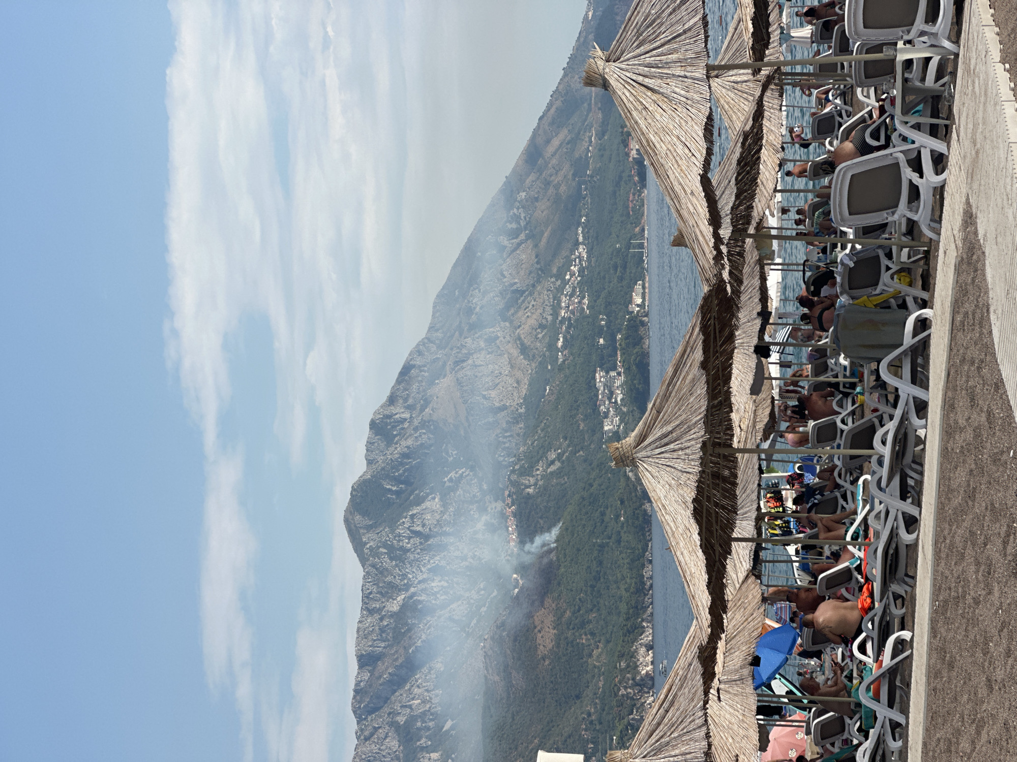 Wildfire smoke rises over Boreti beach on a busy summer day