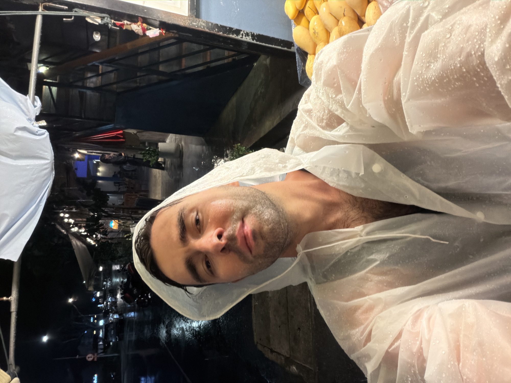Man in white raincoat photographed on Choeng Thale street
