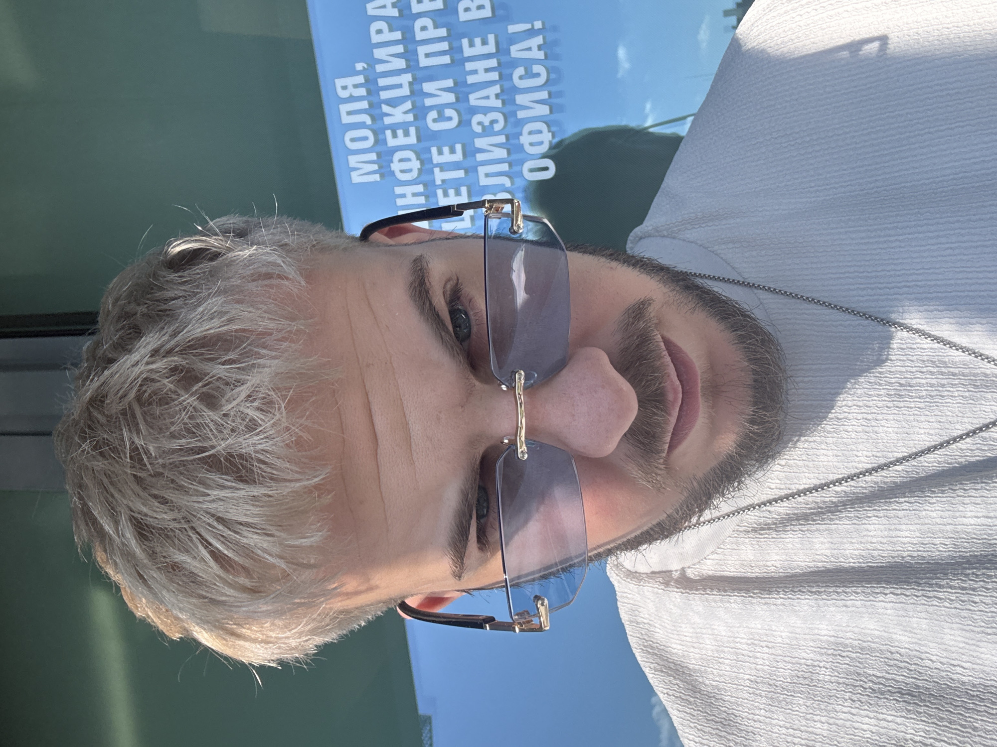 Man in sunglasses photographed near Bulgarian poster in Sofia