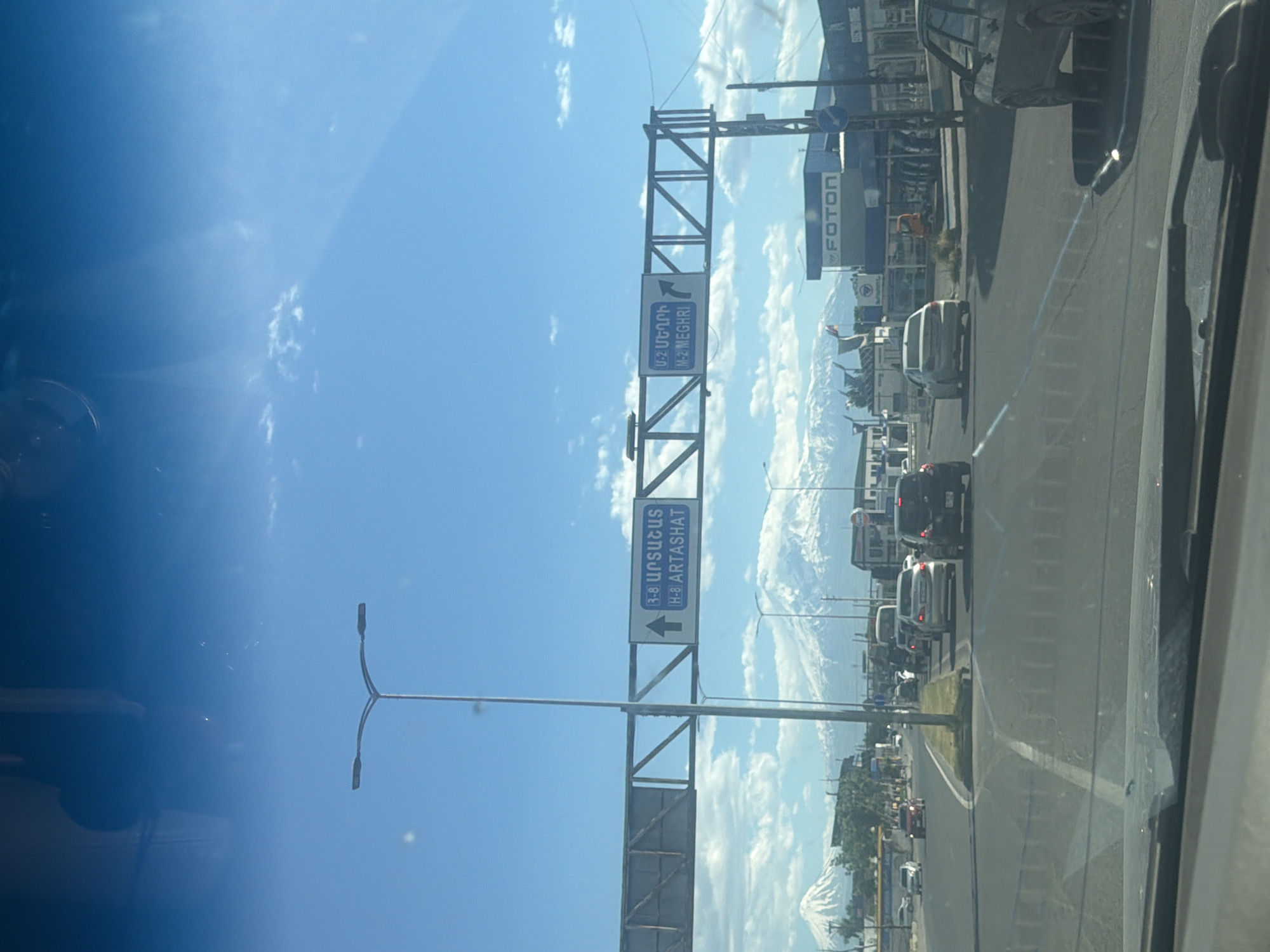 Highway traffic flows toward snow-capped mountains under cloudy skies