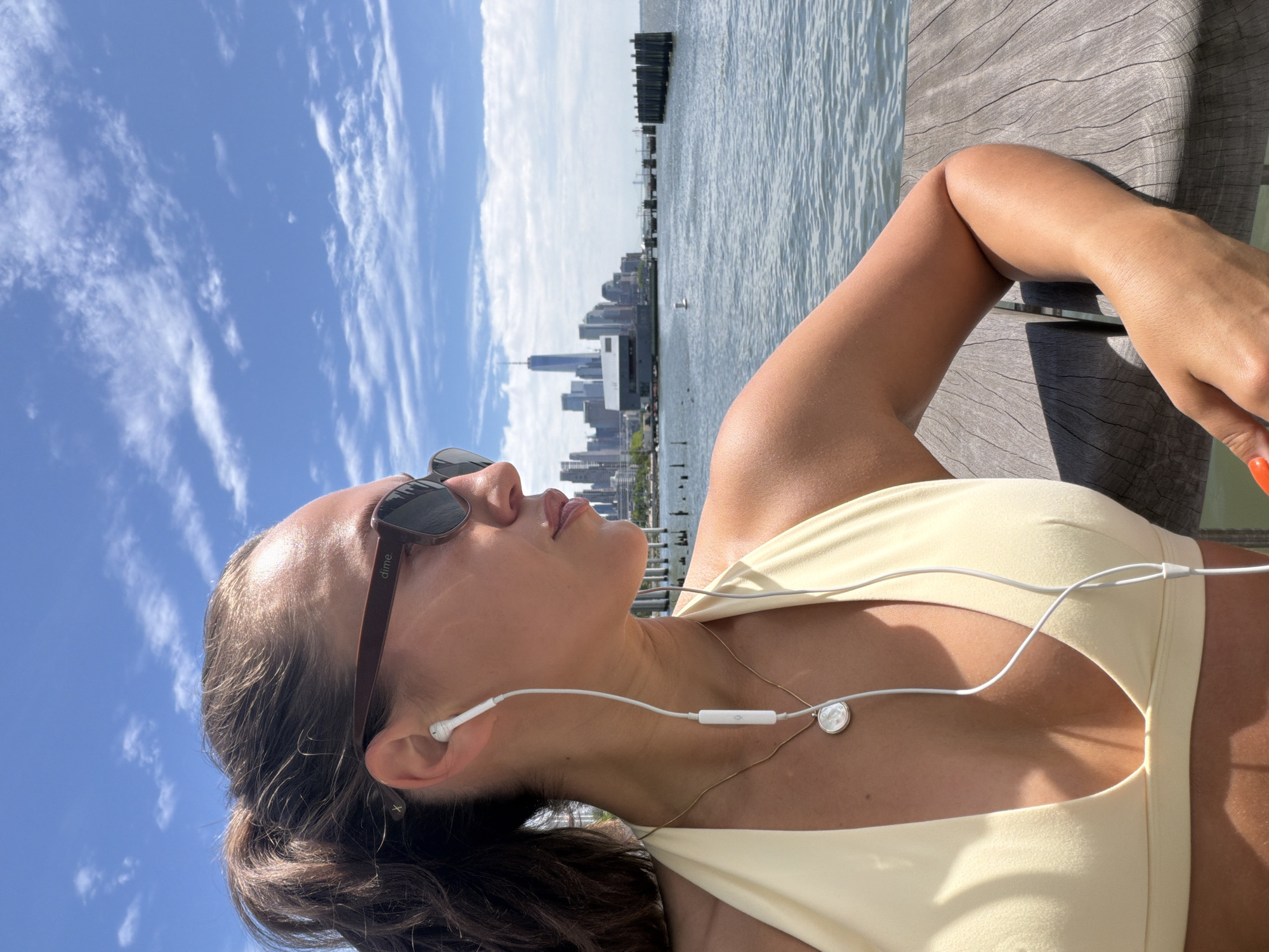Woman relaxes on waterfront deck with Manhattan skyline backdrop