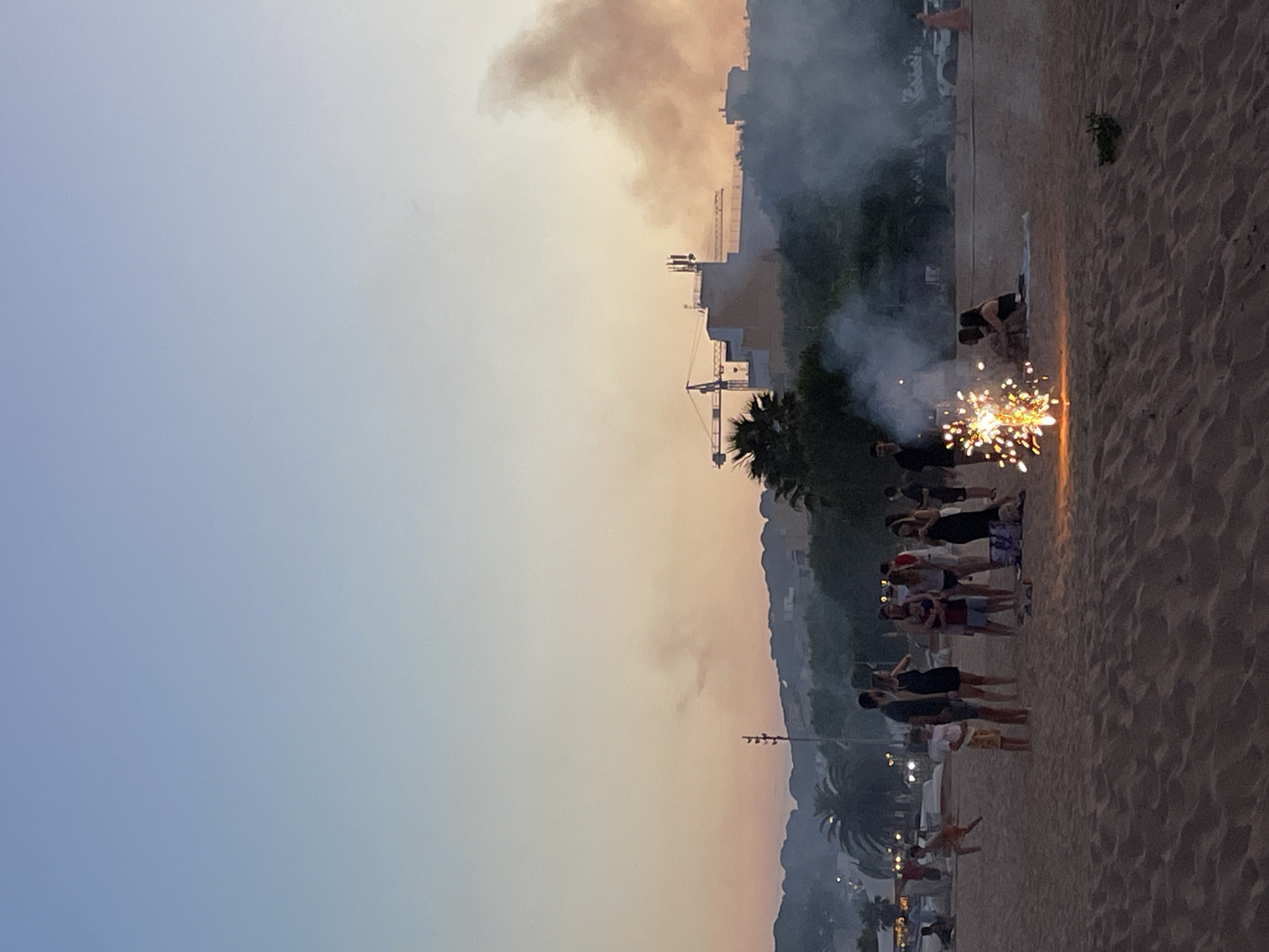 Fireworks and beach crowds at dusk in Calella, Spain