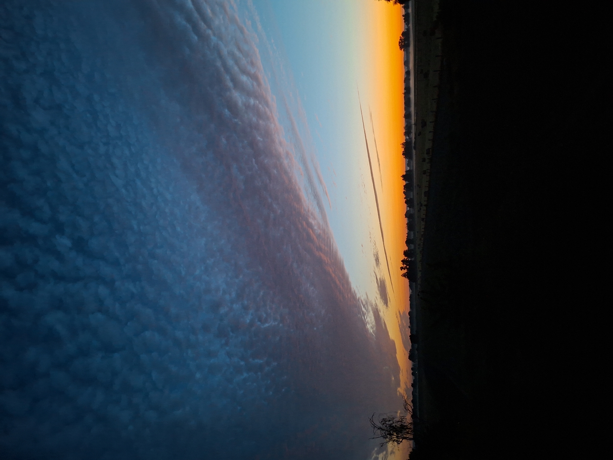 Rural twilight sky caught mid-transition, deep blue to blazing orange