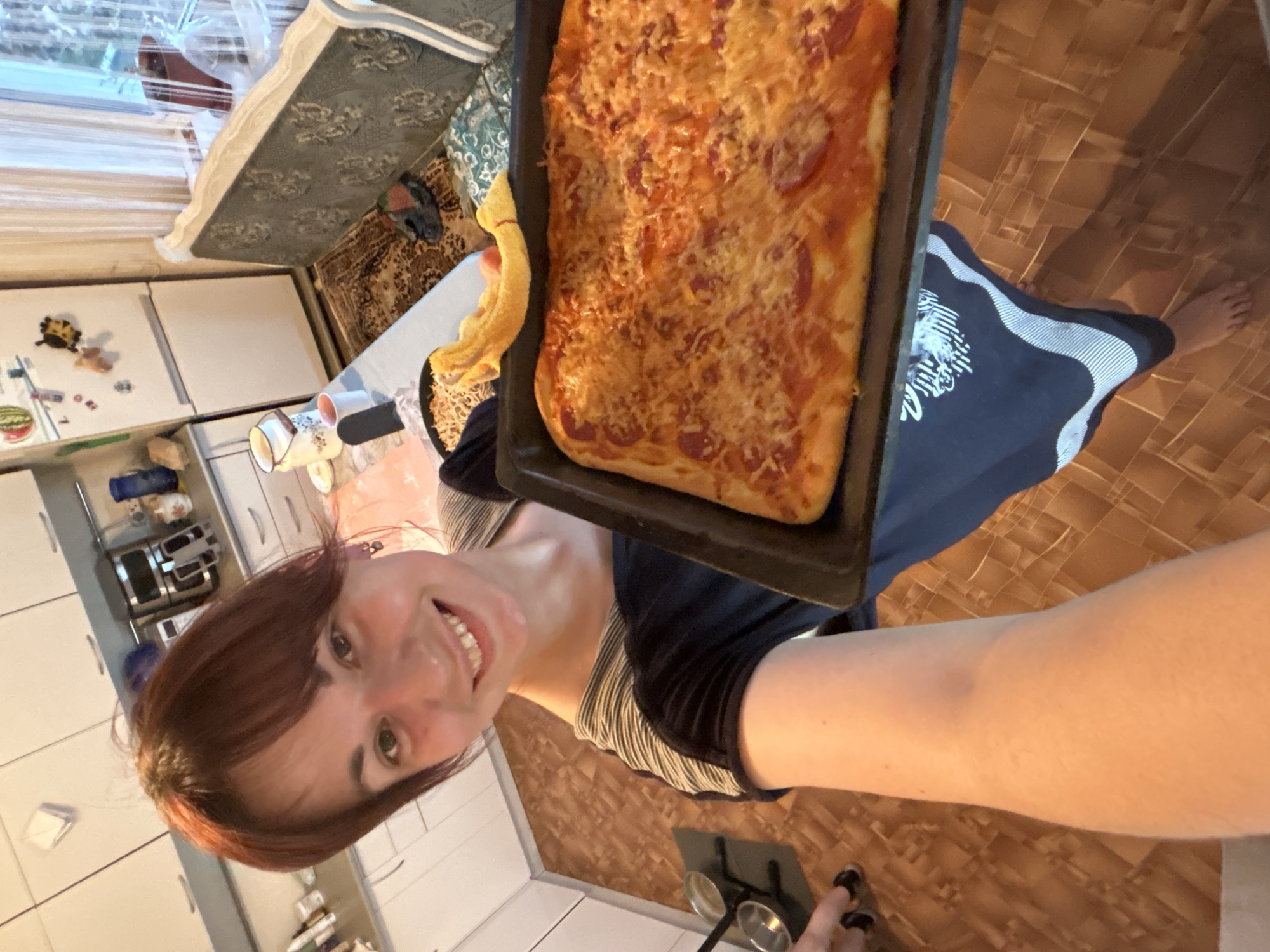 Woman holds homemade pizza in Russian kitchen
