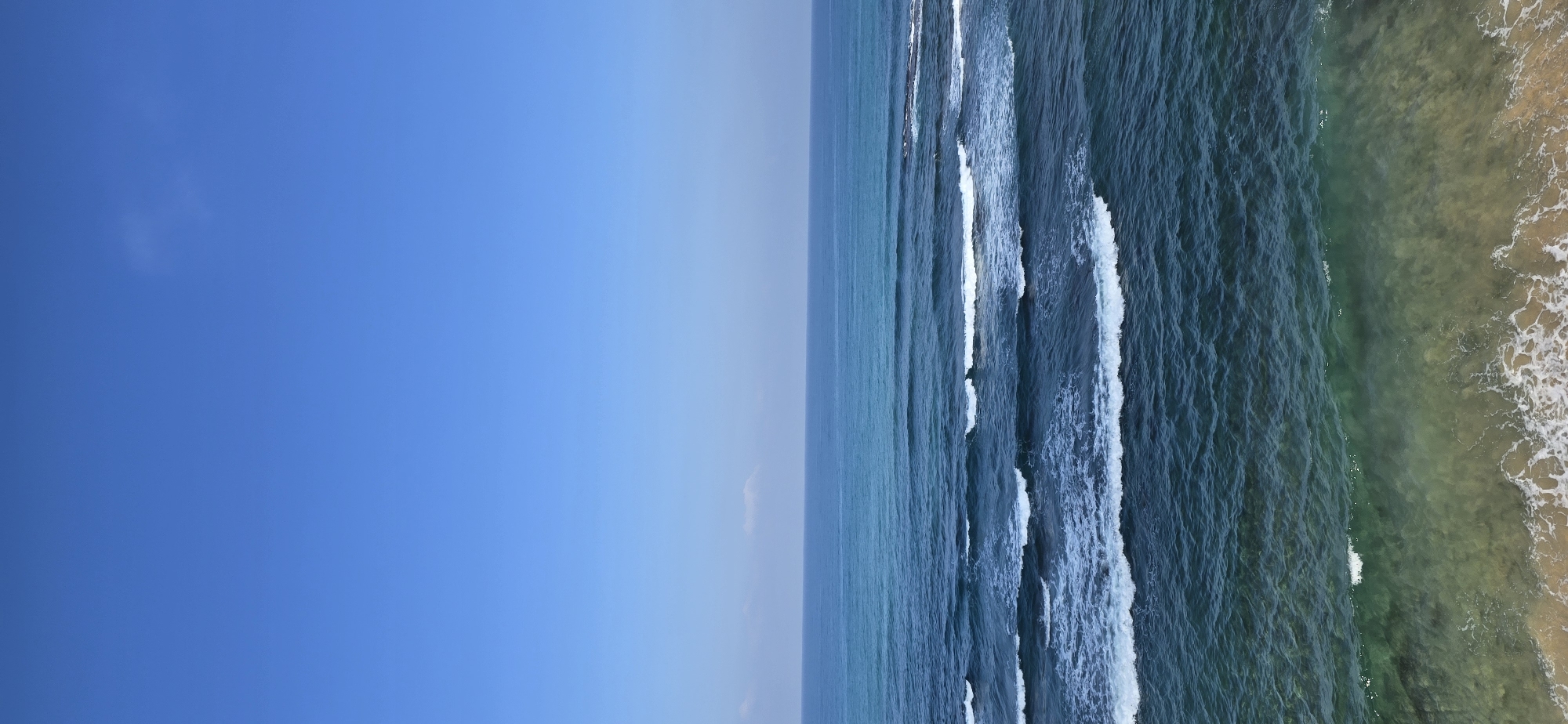 Paddleboarding on a clear-day ocean near a rocky breakwater