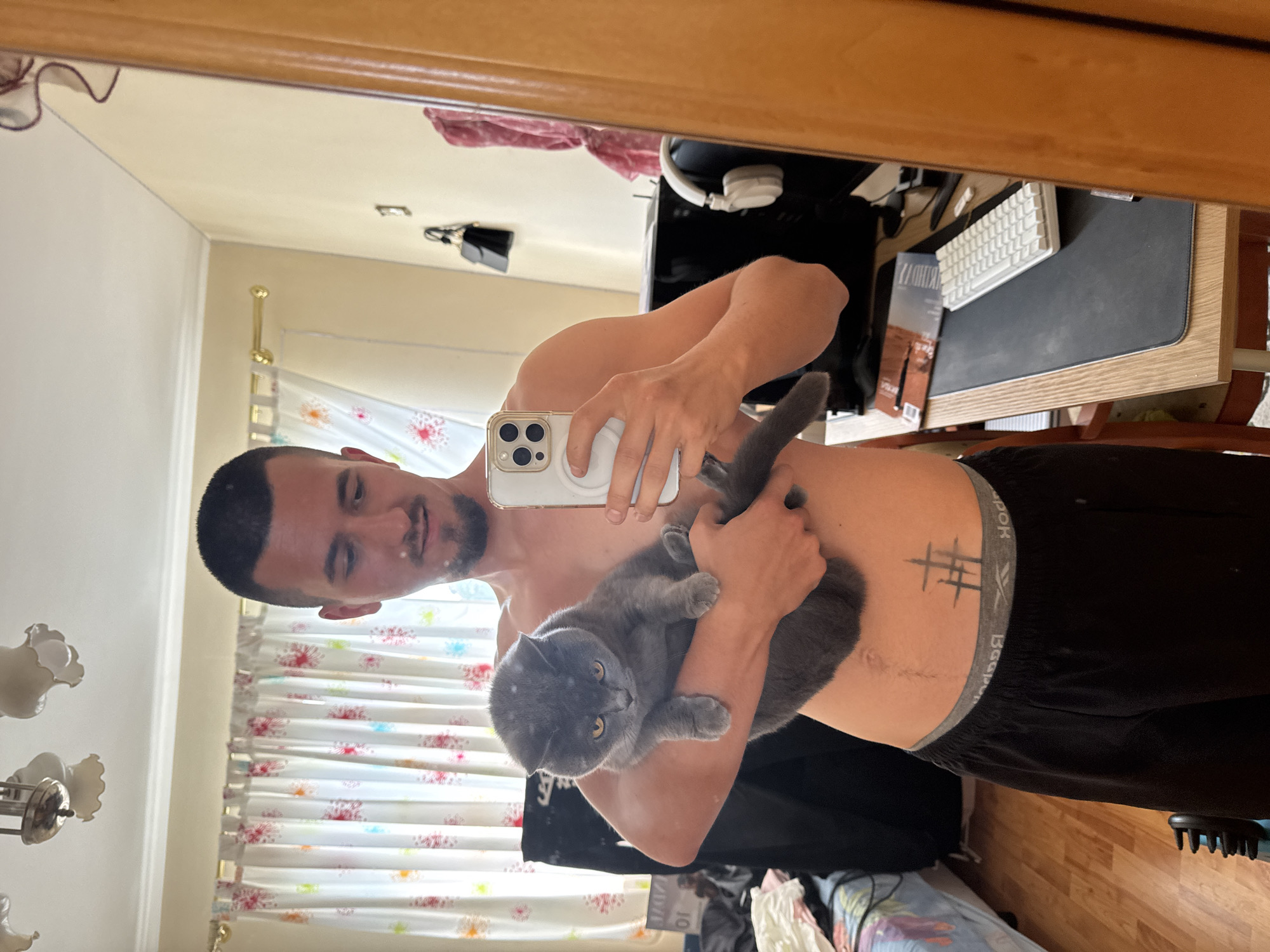 Man takes mirror selfie with grey cat in Sofia home