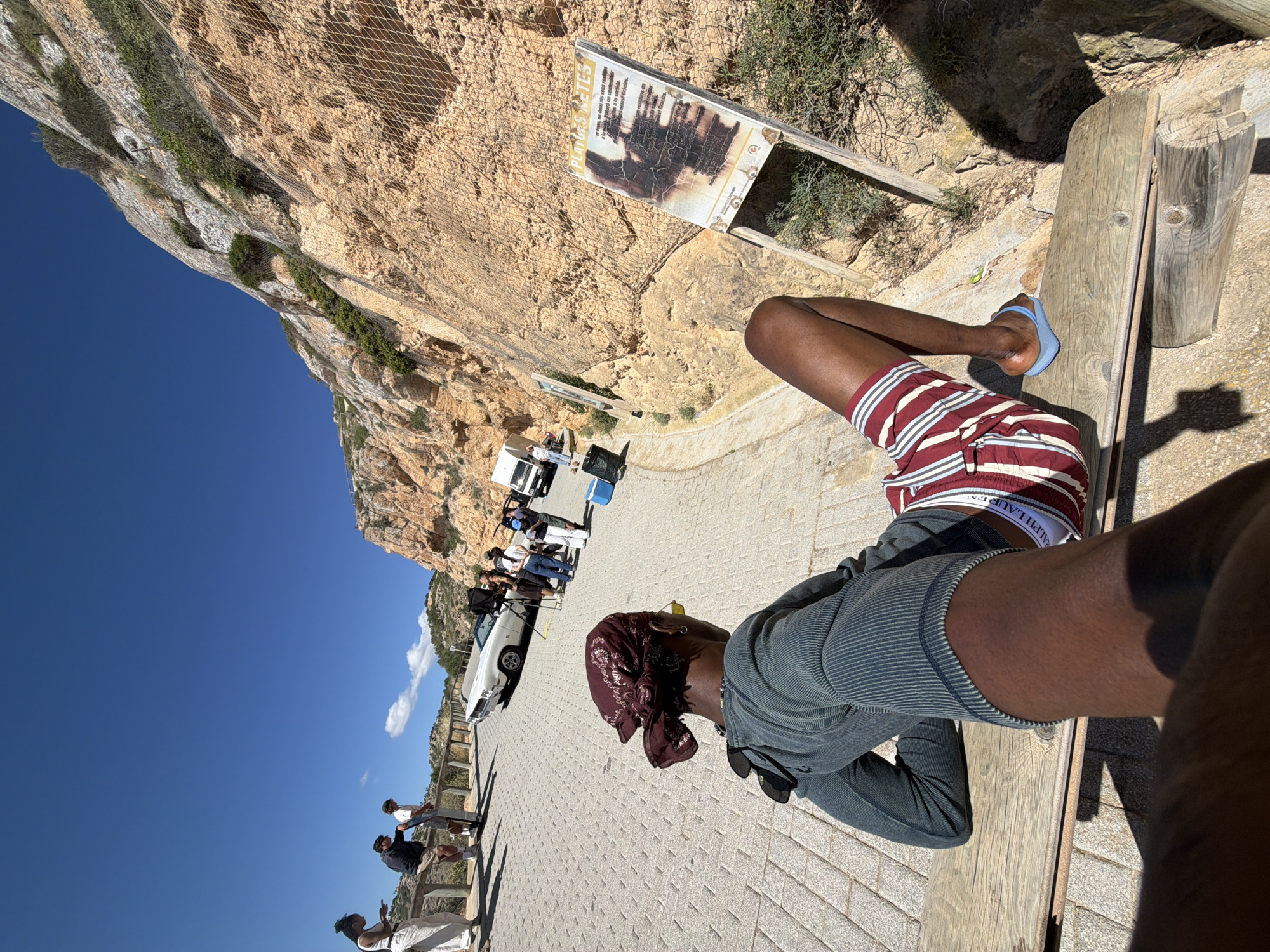 Person relaxes on bench at Cap Blanc, Llucmajor