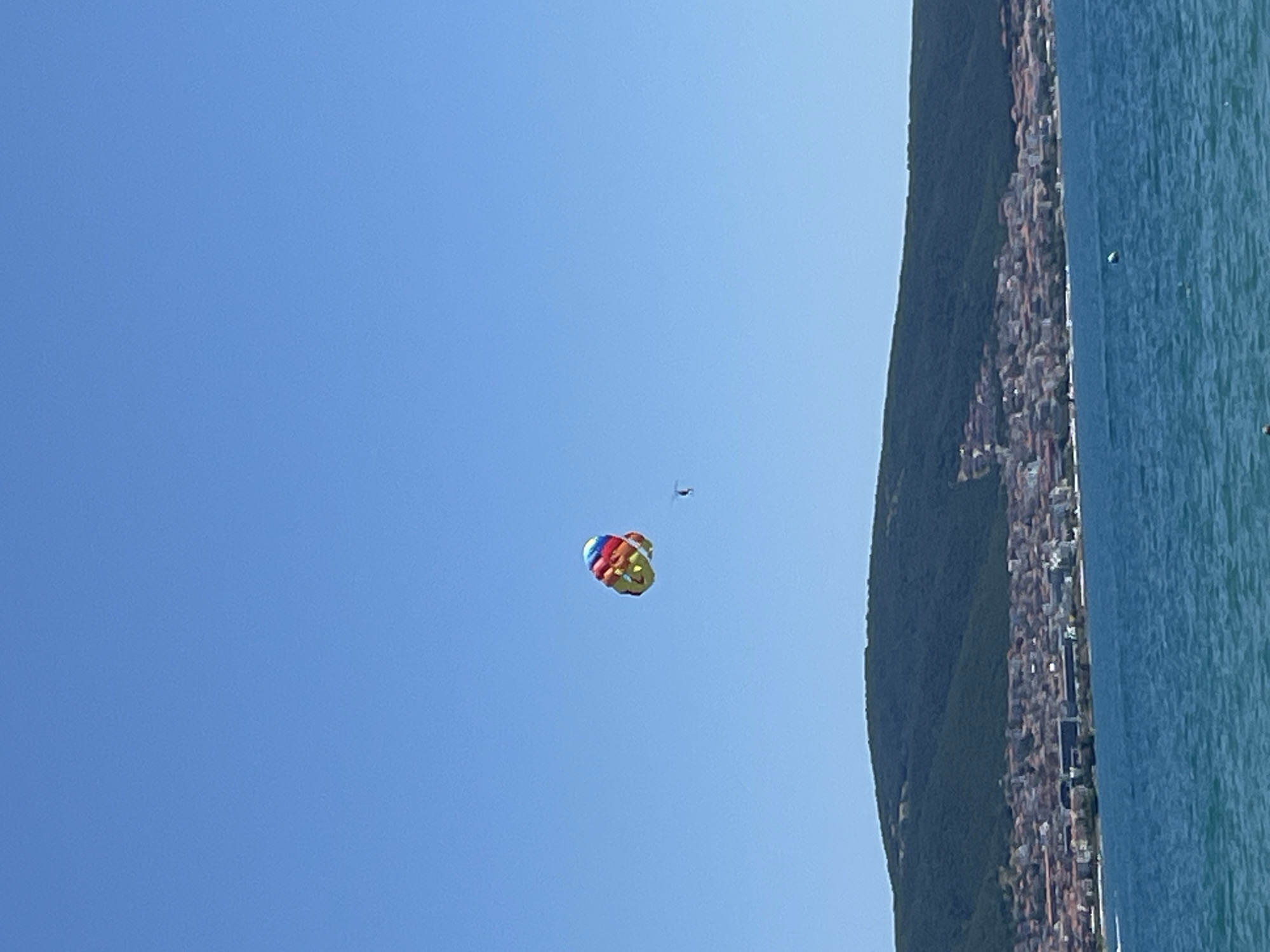 Crowded summer beach day at Nesebar with parasailing overhead