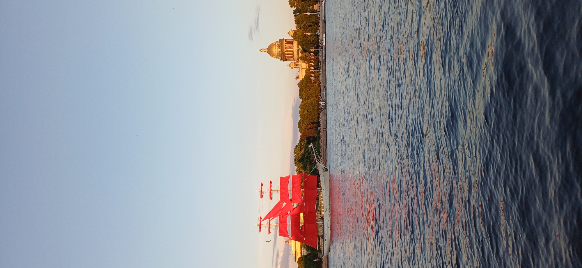 Red-sailed ship draws crowds during sunset passage through Saint Petersburg