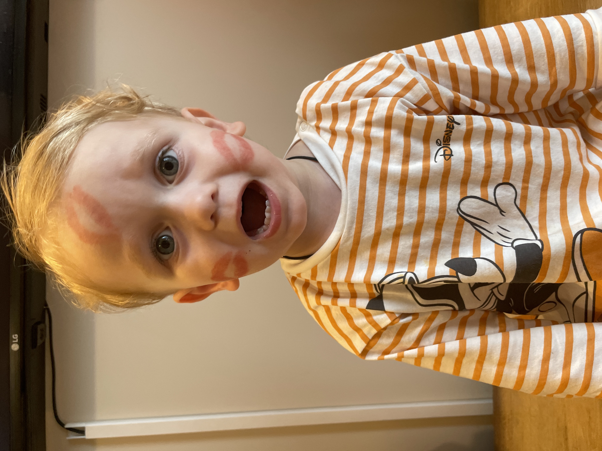 Child photographed with lipstick marks on face and cheek