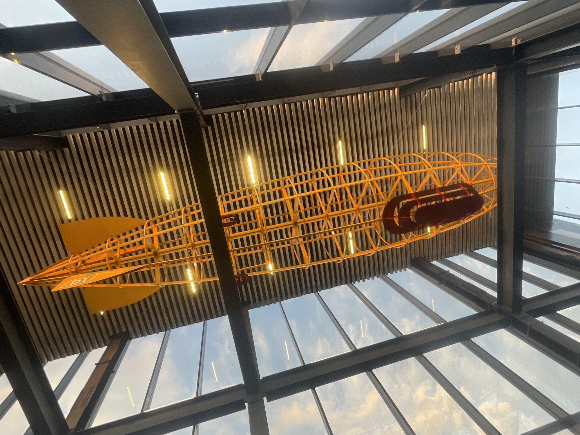 Yellow skeletal airship model displayed in modern building ceiling