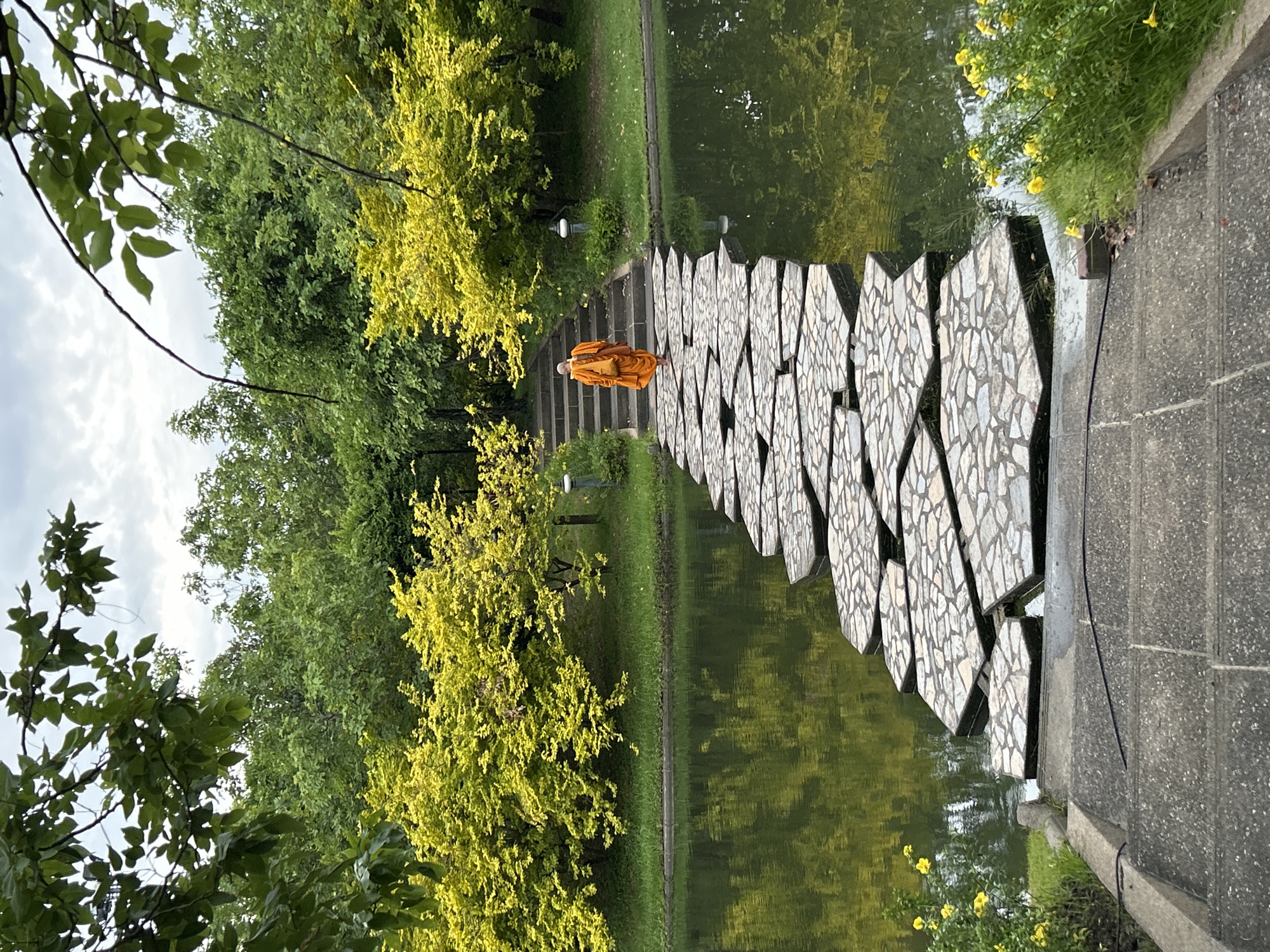 Monk walks stone water path in Bangkok park