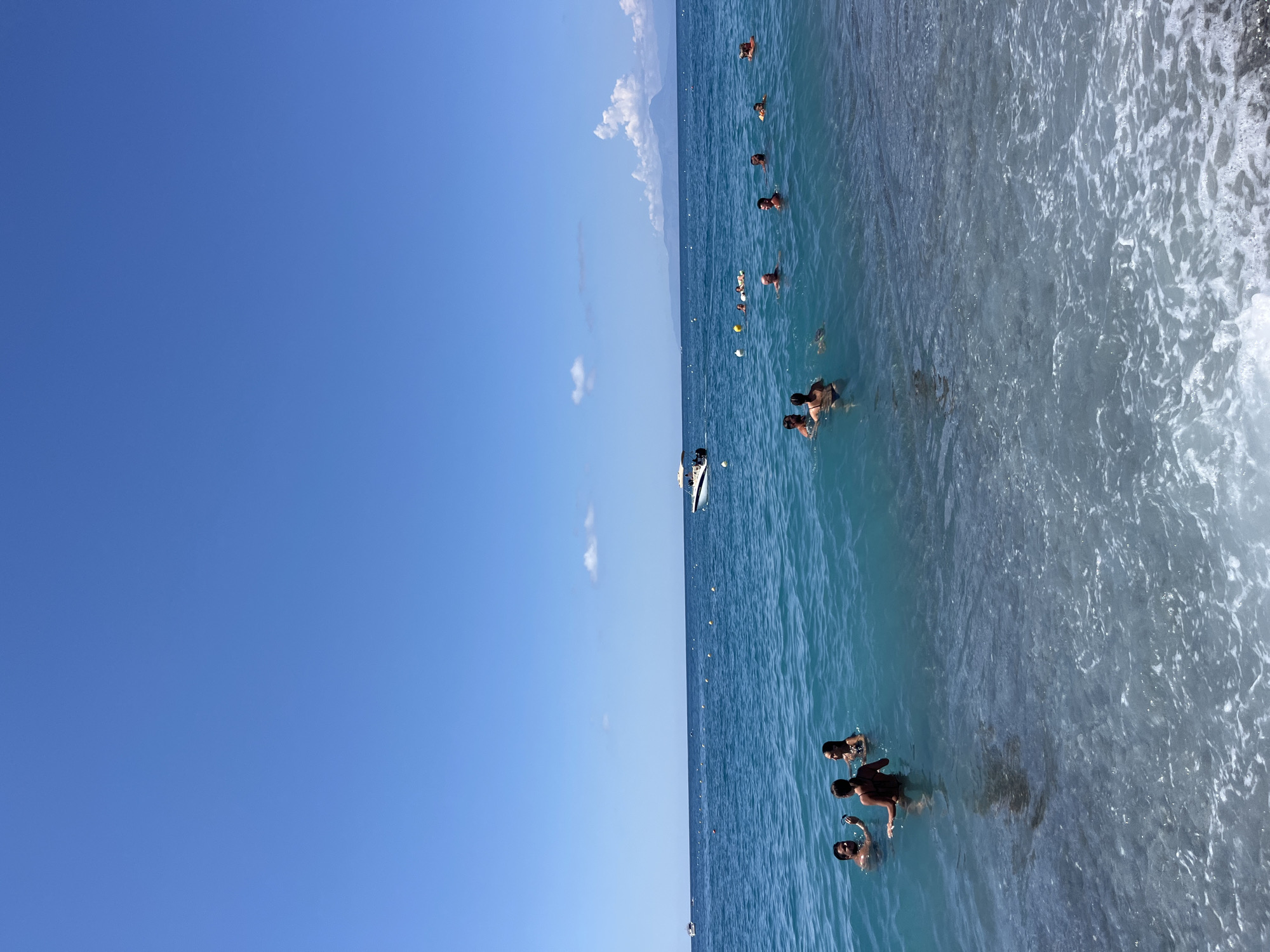 Busy summer beach day in Scalea, boat hauled by excavator