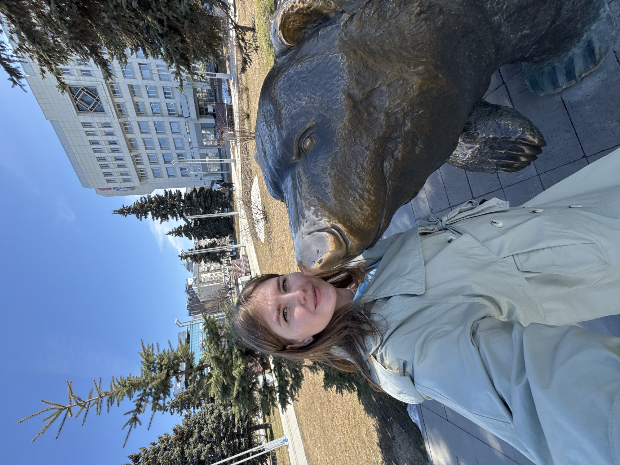 Tourist poses with bronze bear statue in Perm