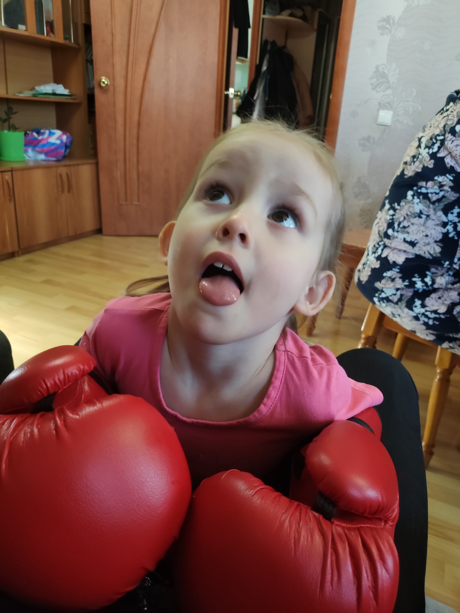 Child poses playfully with boxing gloves in Russia
