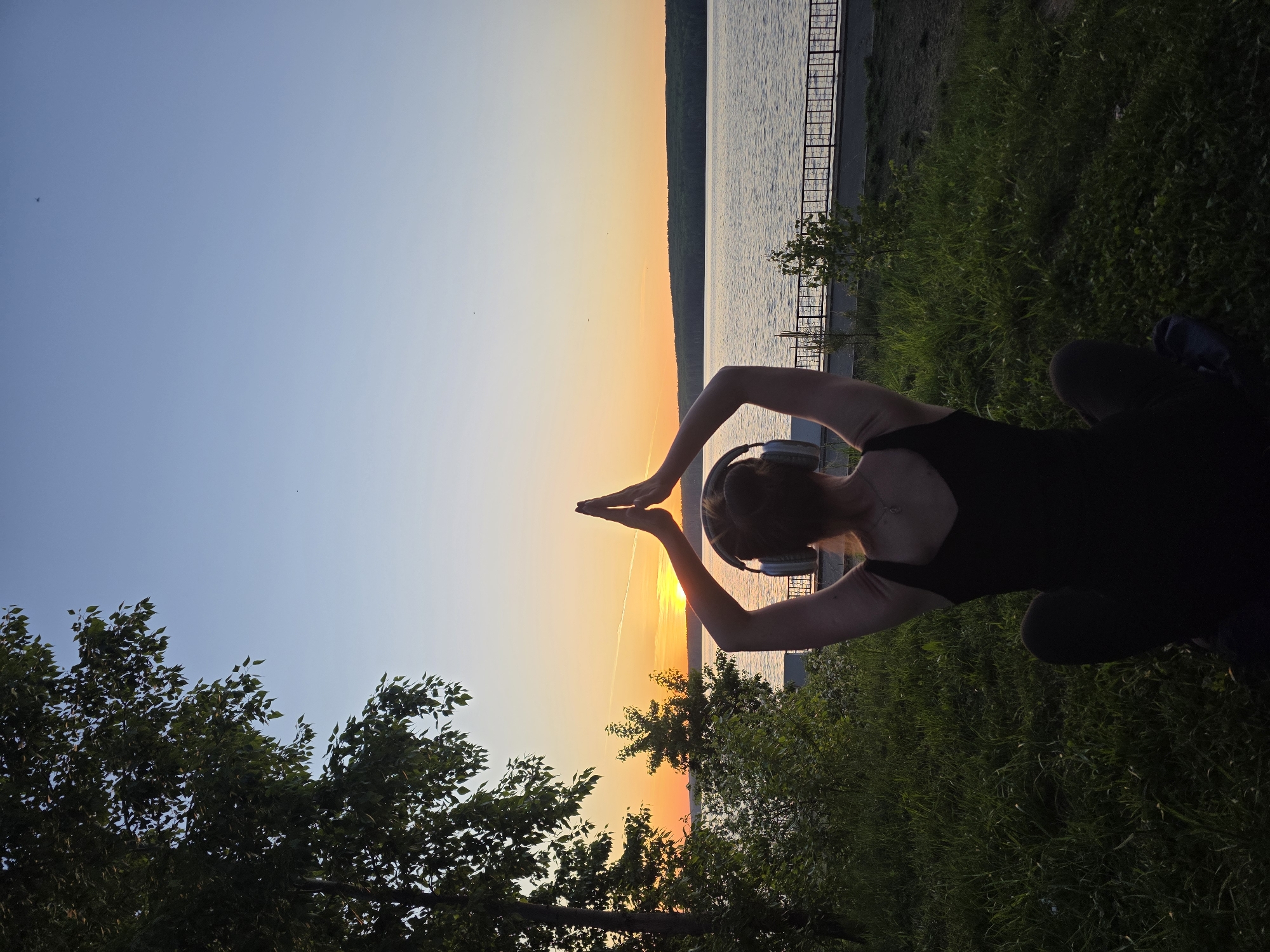 Person practices yoga poses at waterfront during sunset in Russia