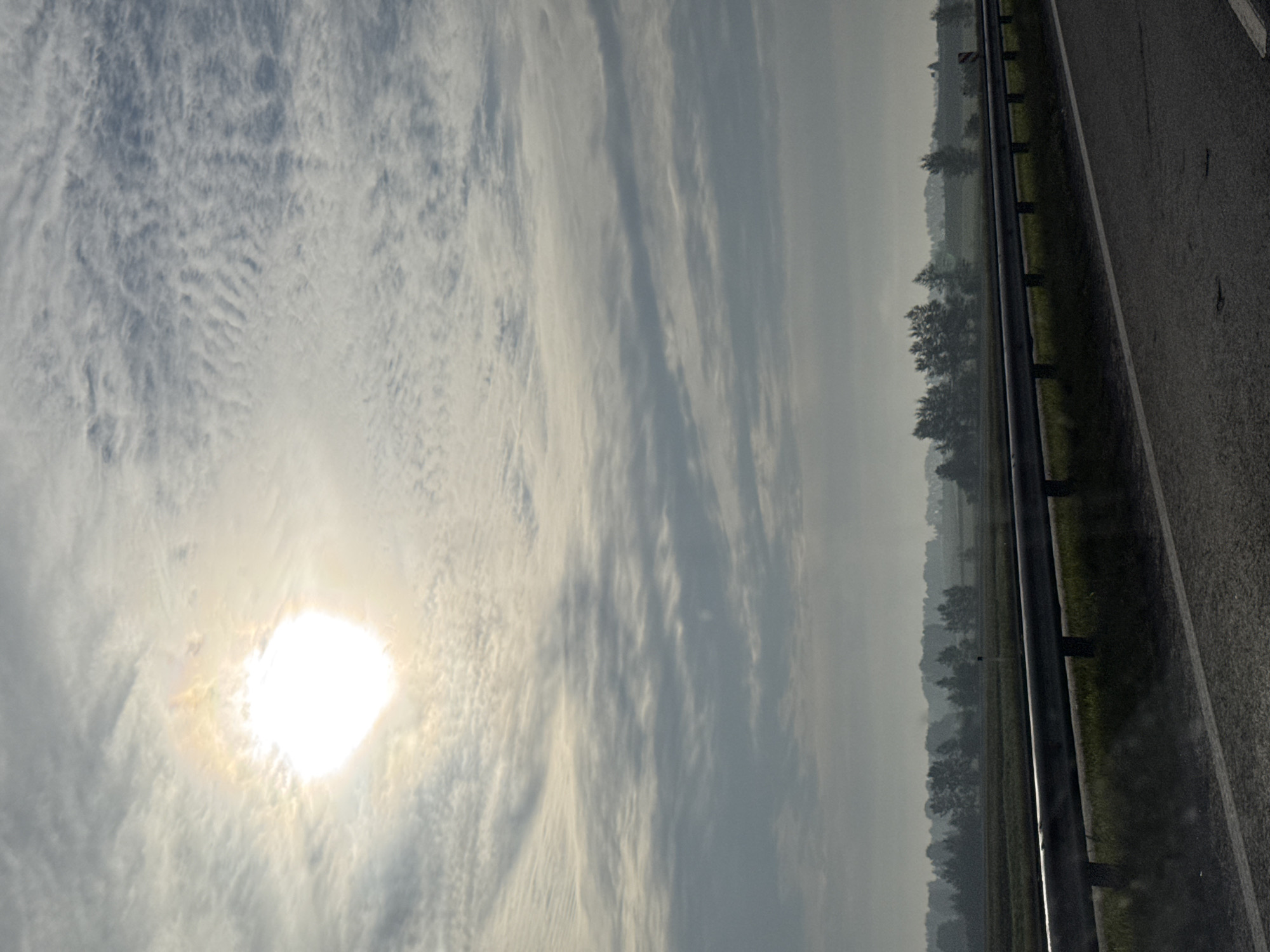 Highway drive through open rural landscape under a hazy sun