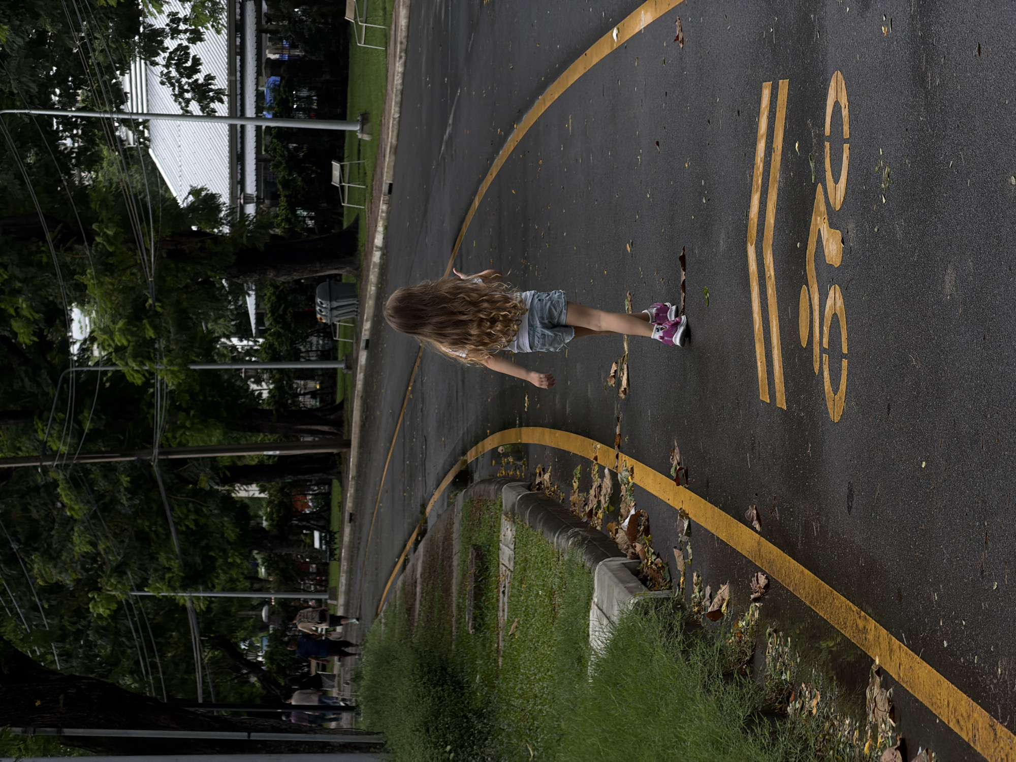 Child walks through Bangkok park on rainy morning