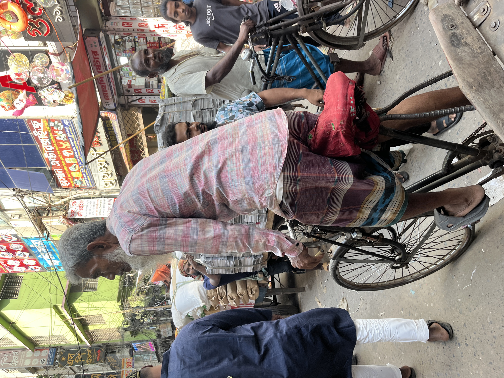 Morning commerce bustles through Dhaka streets with traditional transport