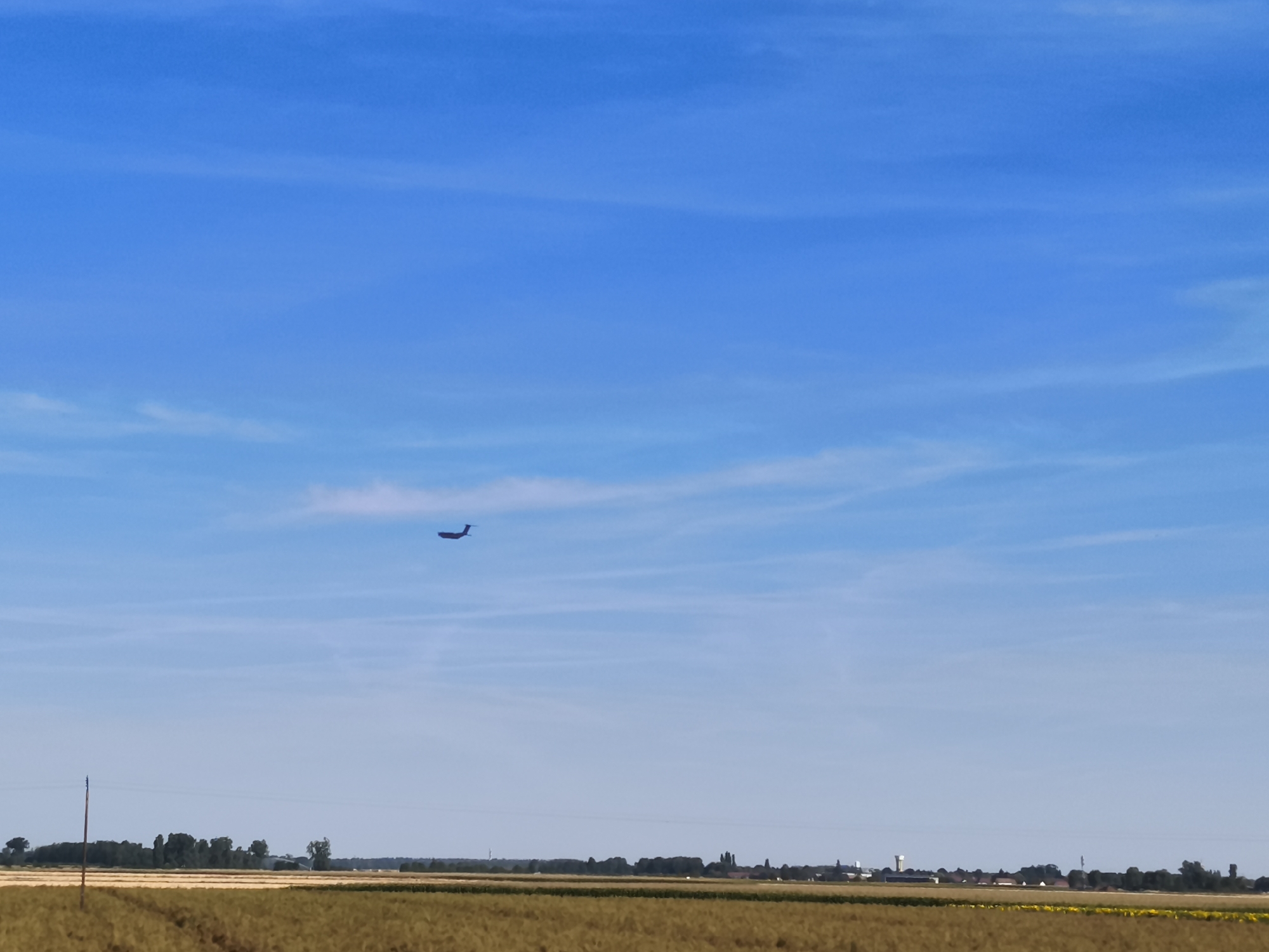 Airplane crosses clear skies over rural French countryside