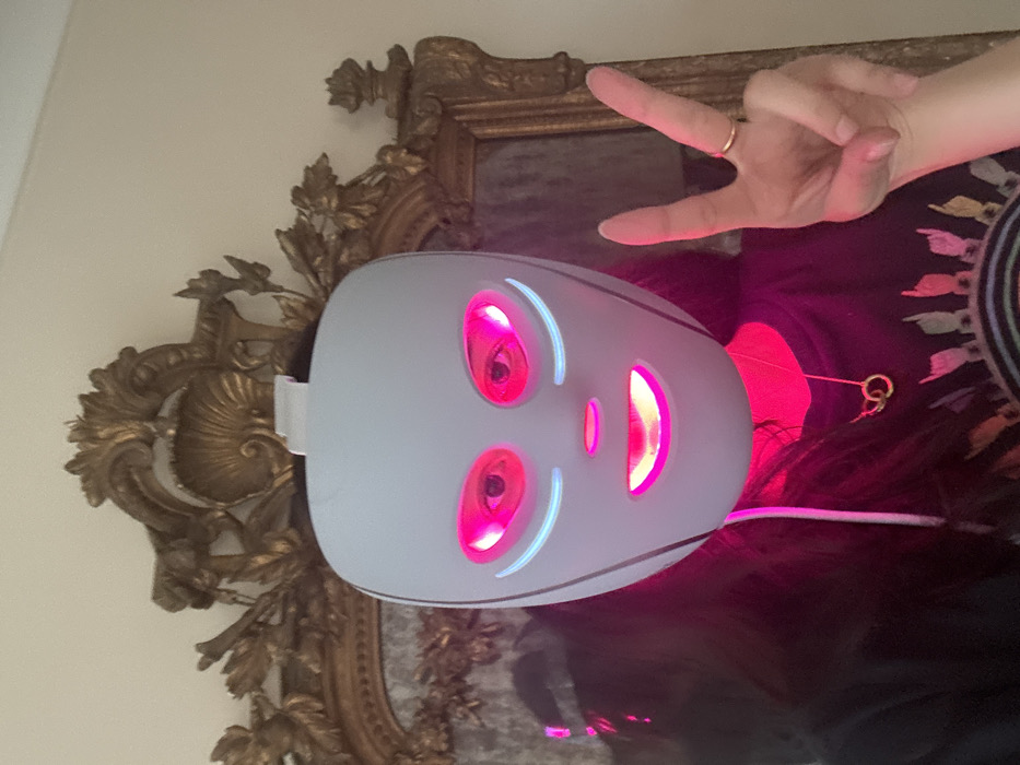 Person documents morning routine wearing glowing LED face mask