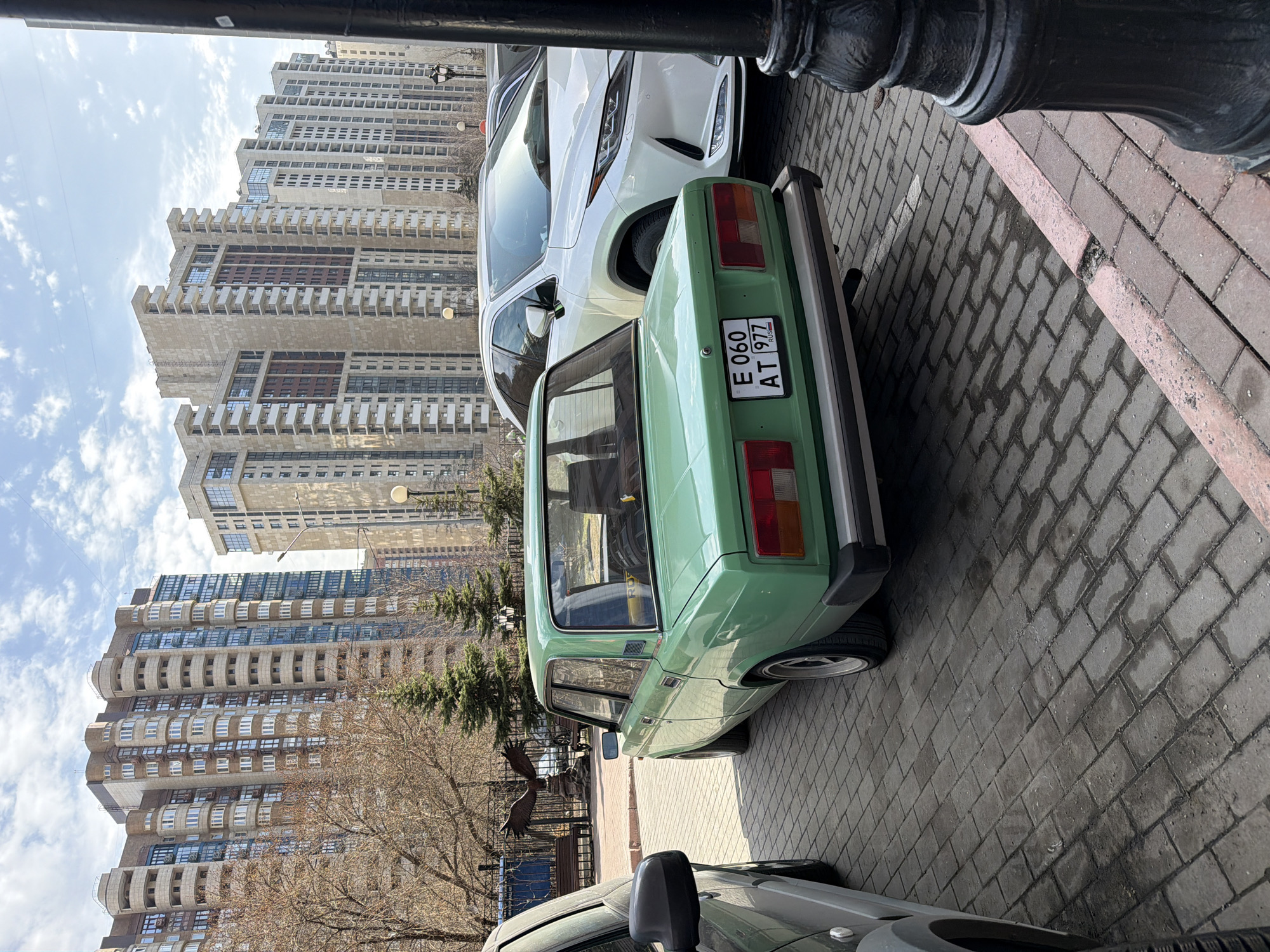 Green Lada parked on Moscow street amid residential buildings